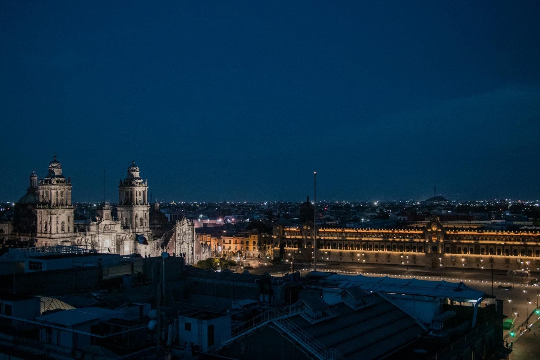 Nighttime aerial view of Mexico City’s historic center showing the Metropolitan Cathedral and the illuminated Zócalo main square.