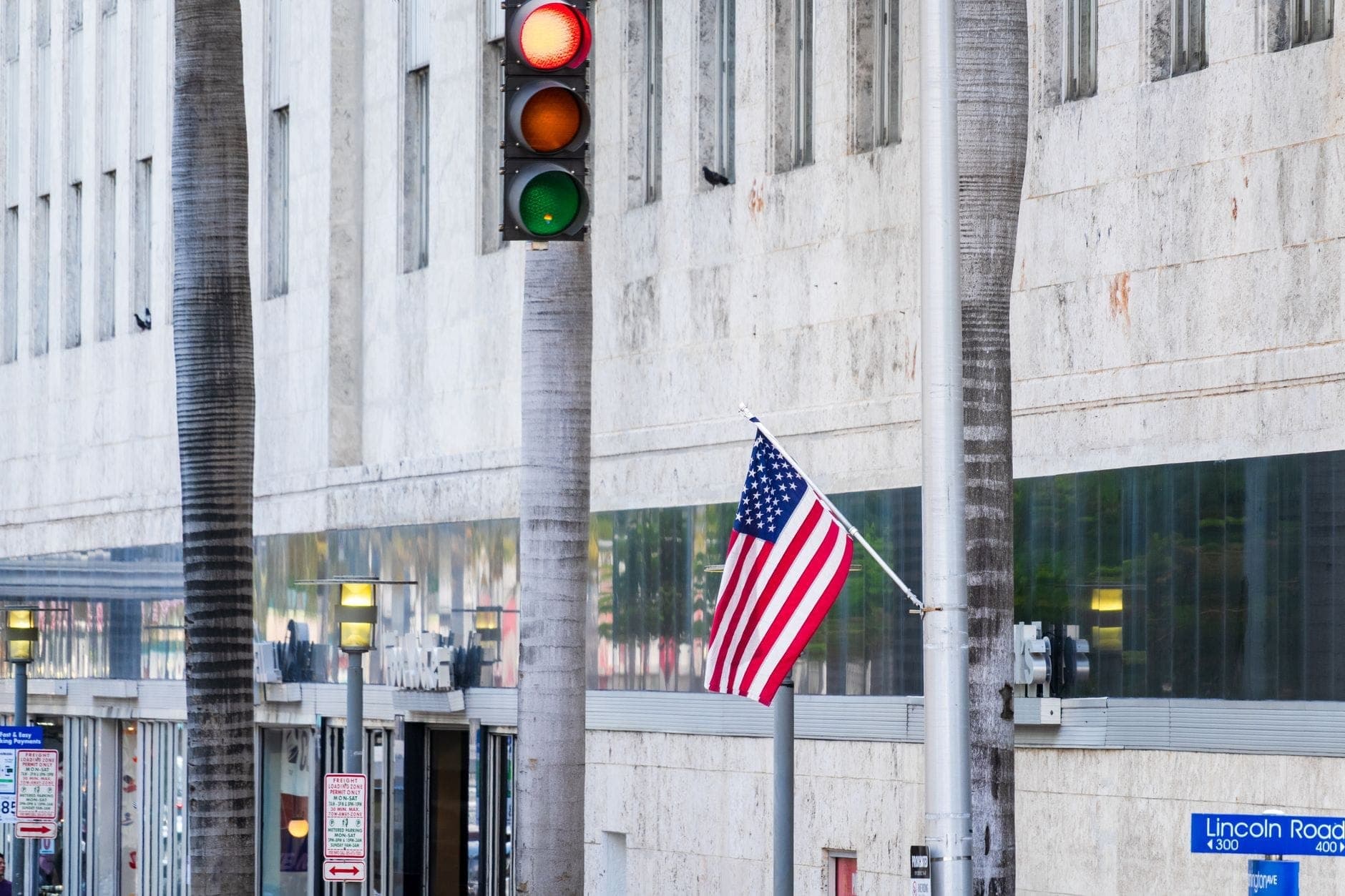 Scène de rue avec panneau Lincoln Road, palmiers et façade d'immeuble à South Beach, Miami en journée