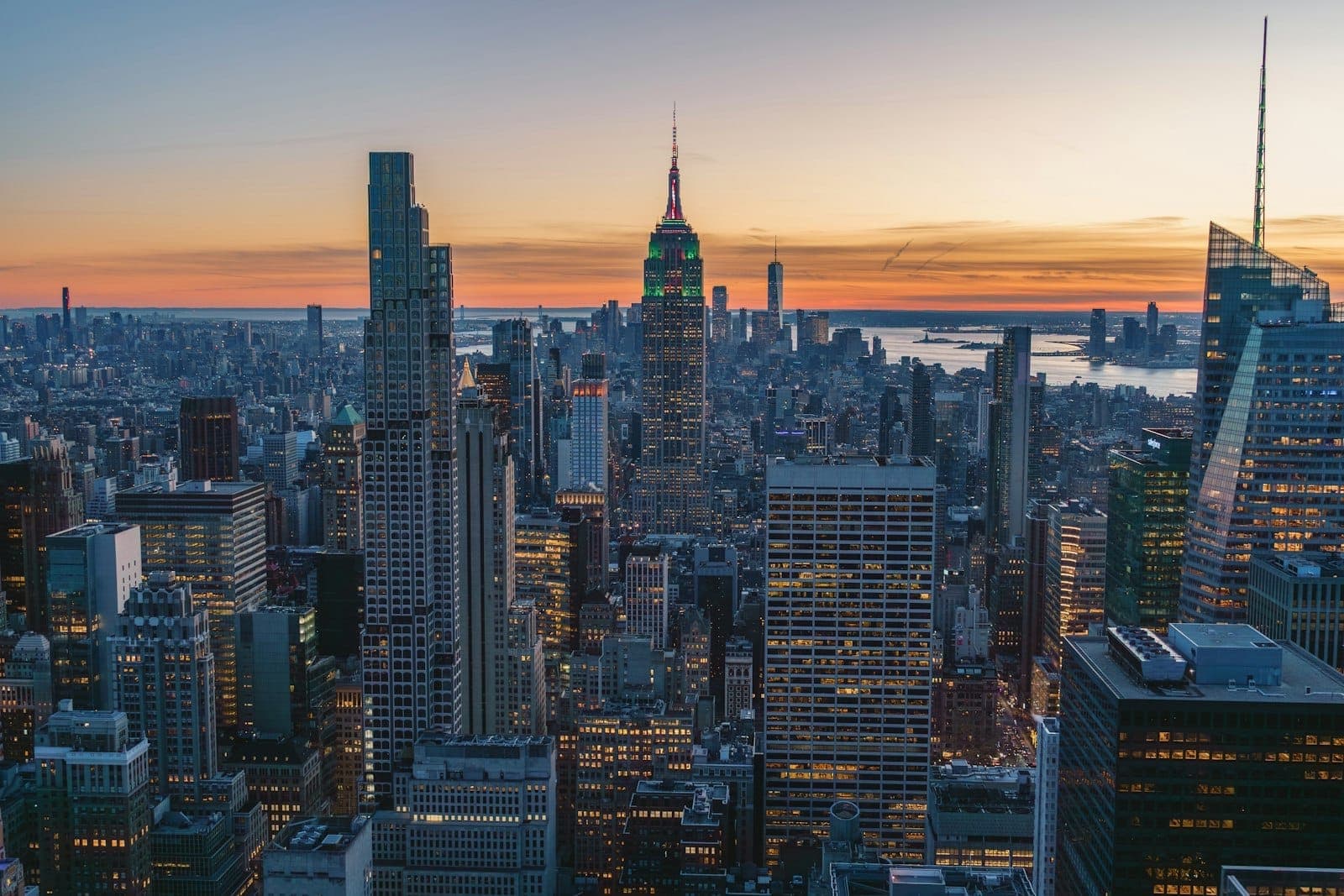 วิวพระอาทิตย์ตกสวยงามเหนือมิดทาวน์ แมนฮัตตัน ตึก Empire State โดดเด่นท่ามกลางตึกระฟ้าและแสงไฟเมืองใต้ท้องฟ้าหลากสี