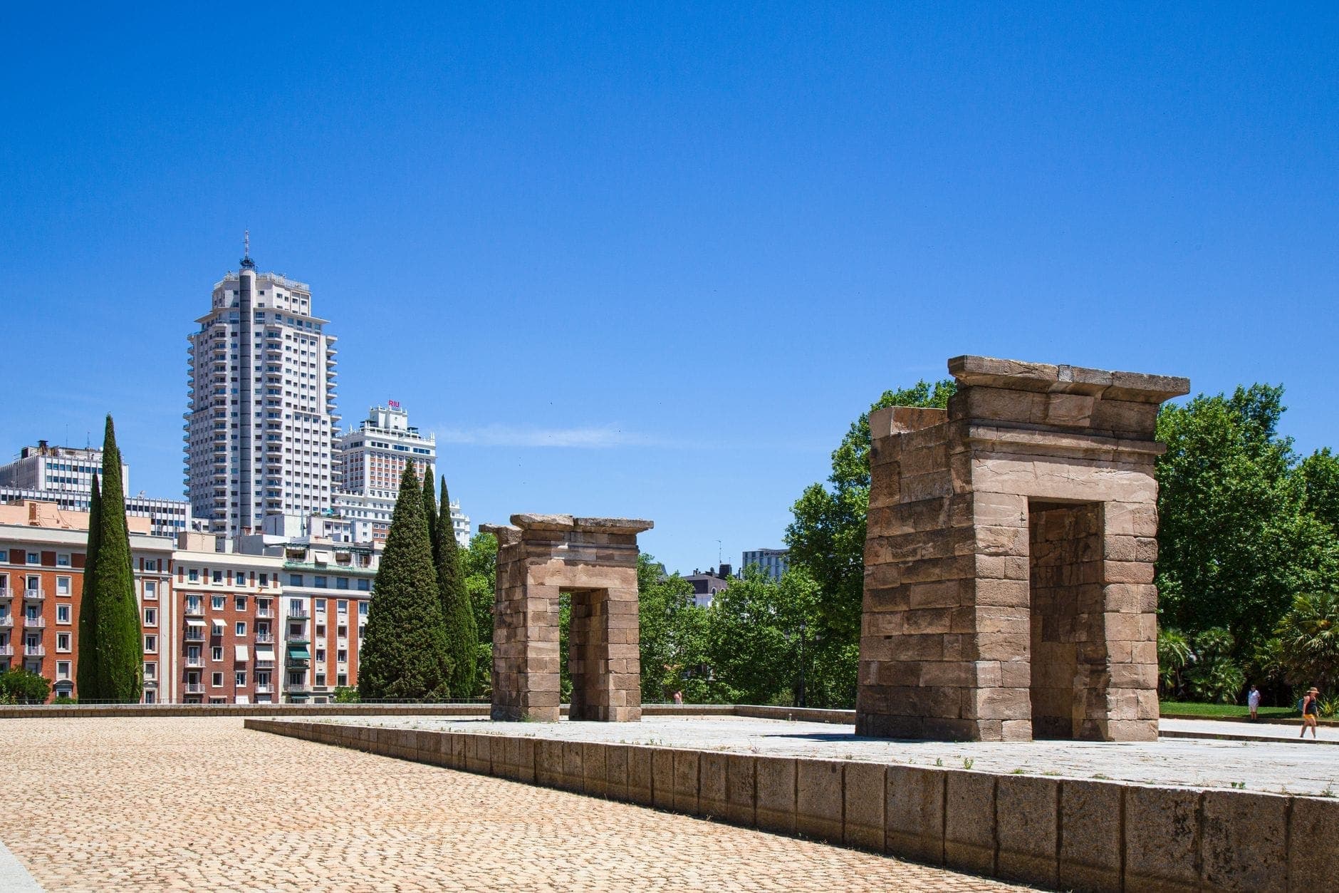 วิหาร Debod ใน Moncloa กรุงมาดริด พร้อมโครงสร้างหินโบราณที่ตั้งตระหง่านท่ามกลางตึกสูงของเมืองและท้องฟ้าสีฟ้าใส