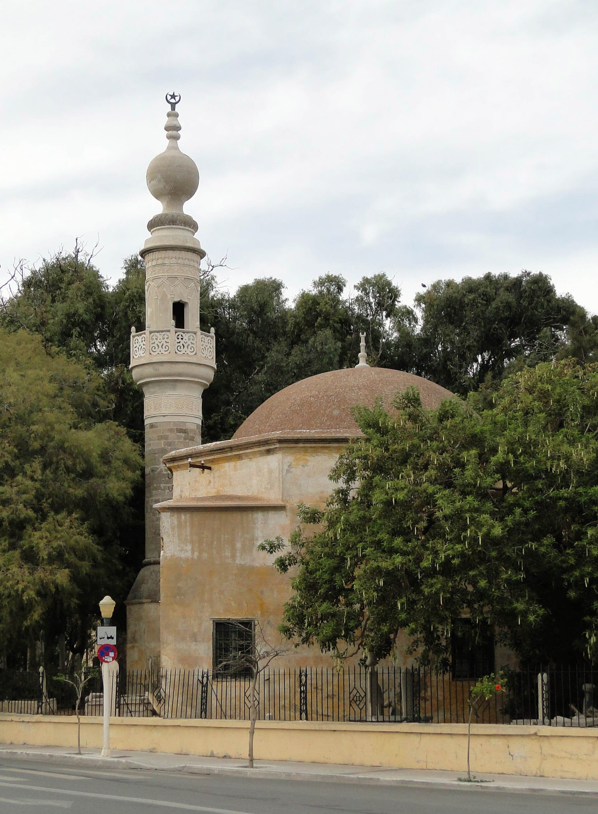 Historique Mosquée de Murad Reis avec toit en dôme et haut minaret, entourée d'arbres matures et d'un vieux cimetière dans la Ville Nouvelle de Rhodes.