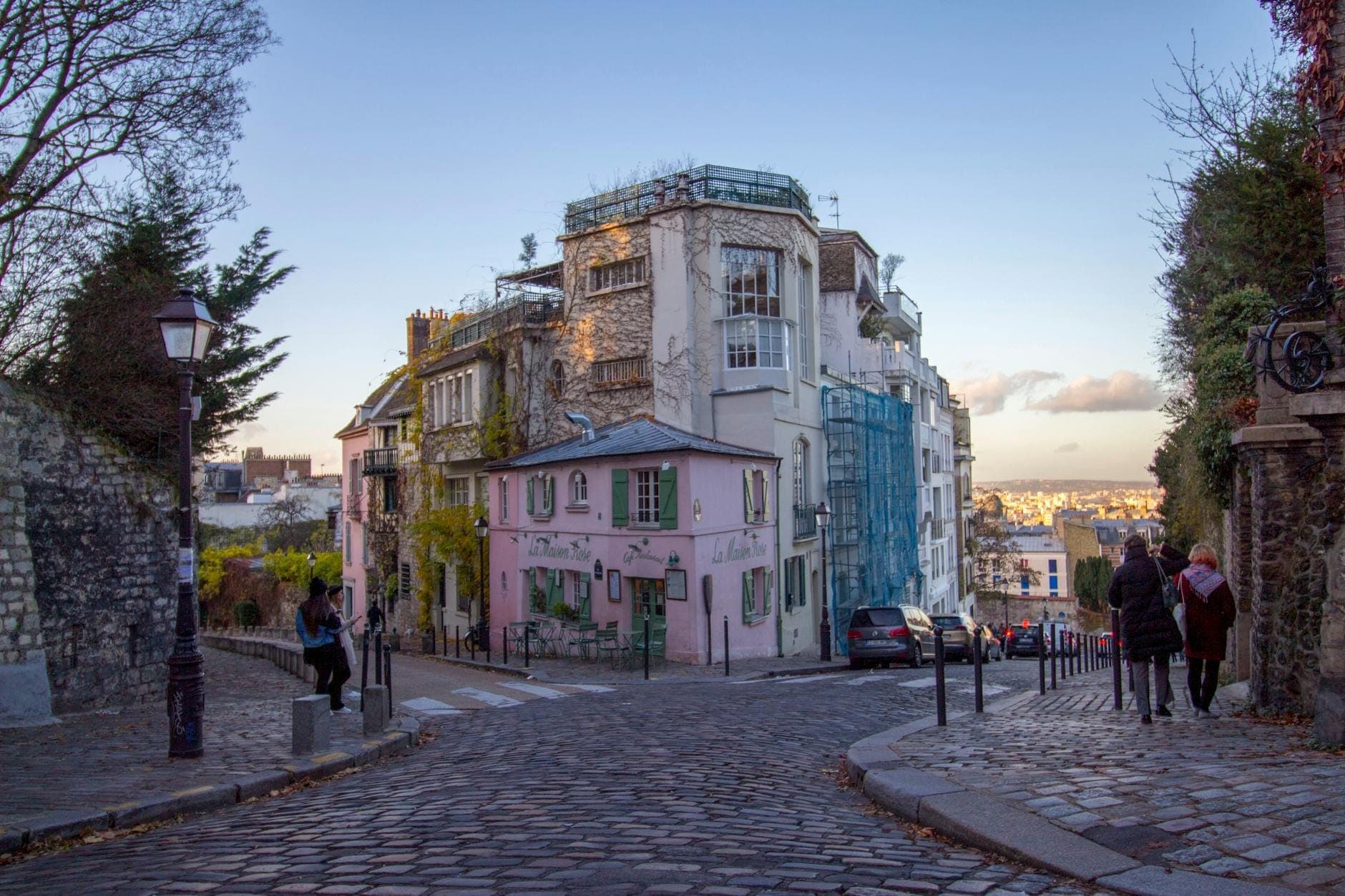 A quiet, cobblestone street in Montmartre lined with charming buildings at sunset, evoking a romantic Parisian village atmosphere.