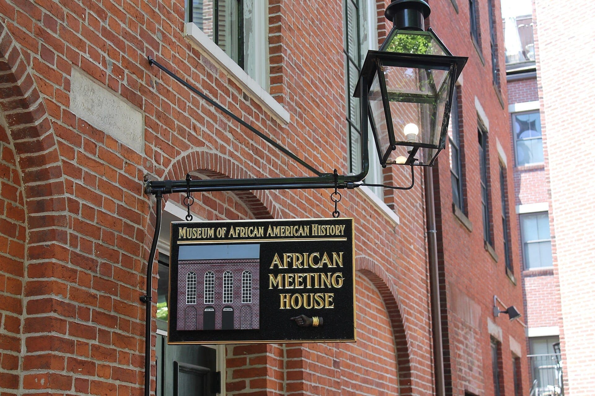 L'enseigne de l'African Meeting House du Museum of African American History est accrochée sur un bâtiment en briques rouges sous une lanterne noire vintage.