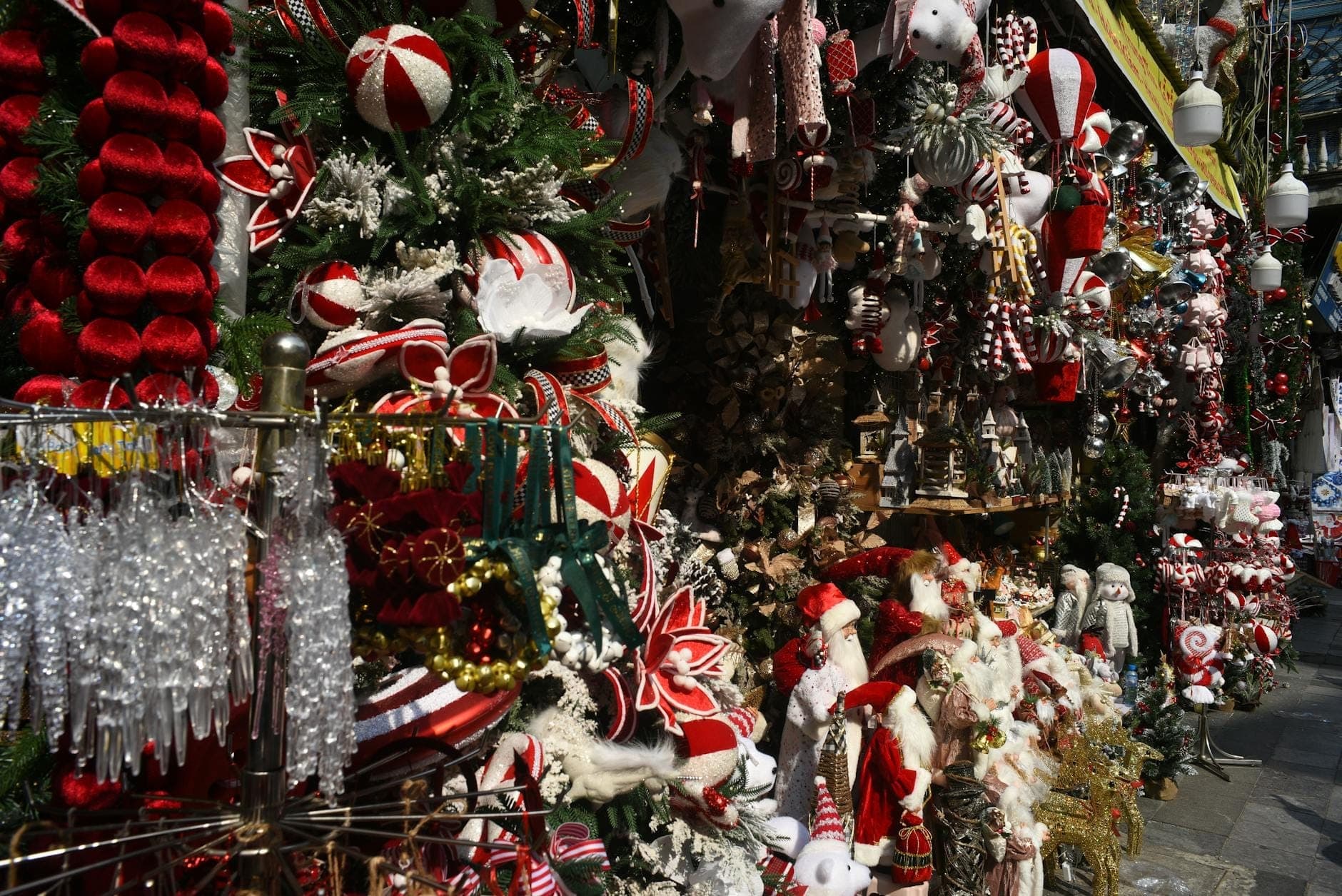 Barraca de mercado de Natal ao ar livre em Nápoles transbordando de decorações natalinas ecléticas, guirlandas e enfeites em uma movimentada cena de rua.