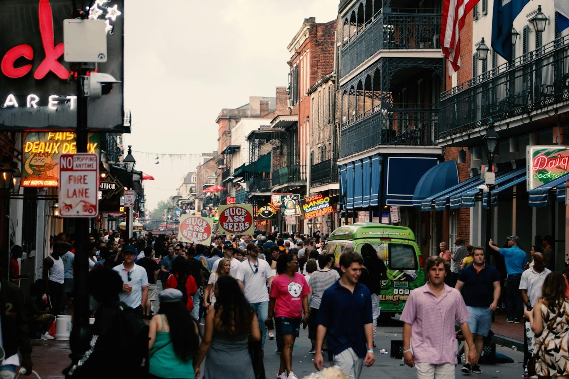 Una vivace scena di strada a New Orleans con folle che camminano tra gli edifici storici del French Quarter e le insegne al neon.