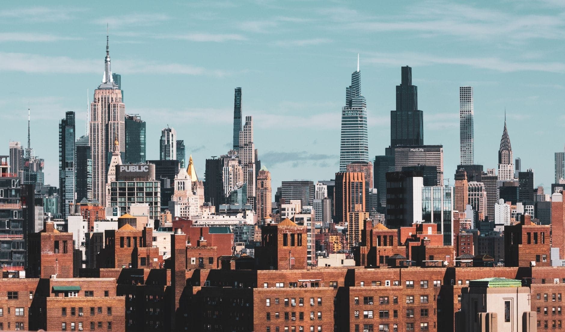 ภาพพาโนรามาของขอบฟ้านิวยอร์กซิตี้ตัดกับตึกแลนด์มาร์กชื่อดัง ทั้ง Empire State, ตึกใหม่สลับกับอาคารประวัติศาสตร์ ท้องฟ้าสว่างสดใส