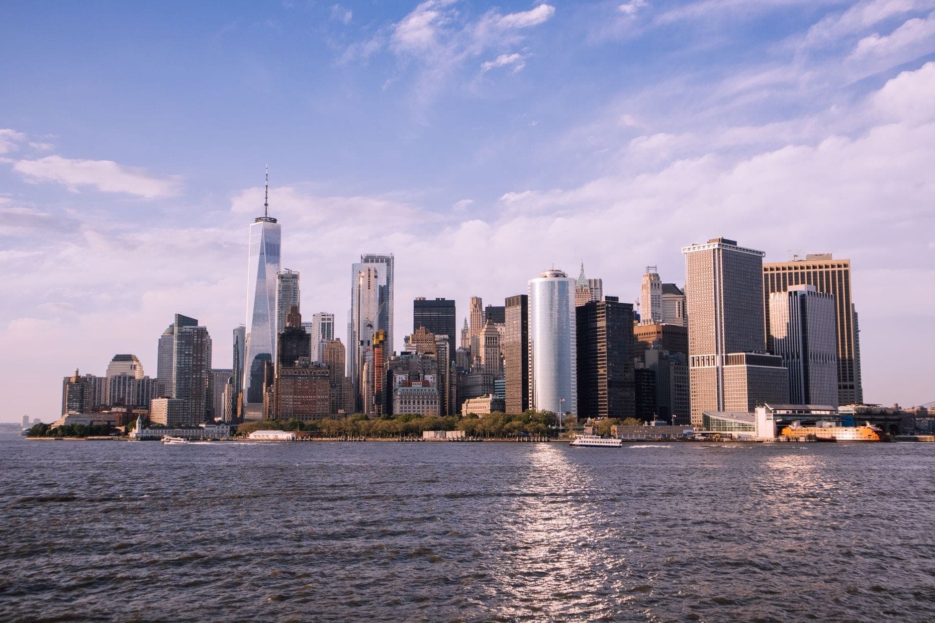 วิวมุมกว้างของเส้นขอบฟ้า Lower Manhattan ในนิวยอร์ก ซิตี้ มองข้ามแม่น้ำฮัดสัน ท้องฟ้าแจ่มใสและแสงสะท้อนผิวน้ำ