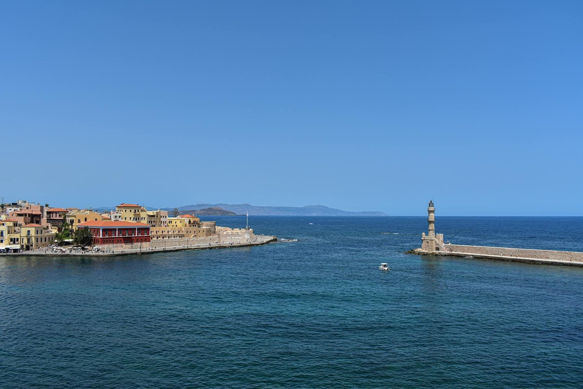 Porto veneziano di Chania con variopinti edifici sul lungomare e il caratteristico faro sotto un cielo azzurro limpido, Creta, Grecia