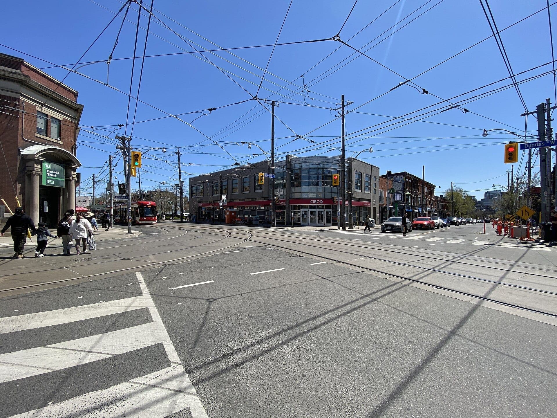 Incrocio tra Ossington Avenue e Dundas Street West a Toronto, con linee di tram, pedoni e un mix di edifici storici e moderni.