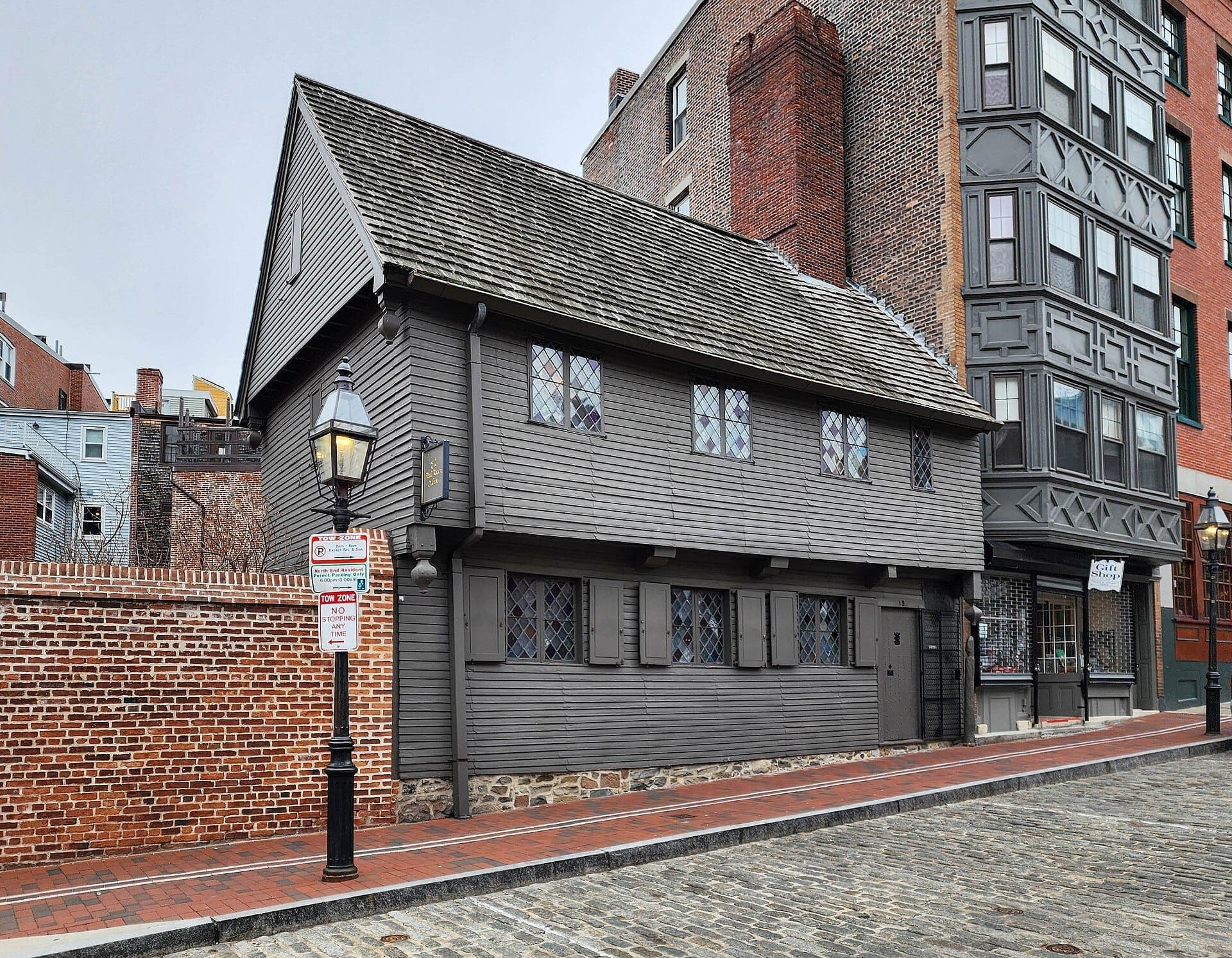 La Paul Revere House, un bâtiment colonial en bois gris avec des fenêtres à petits carreaux en losange, se dresse sur une rue pavée dans le quartier North End de Boston.