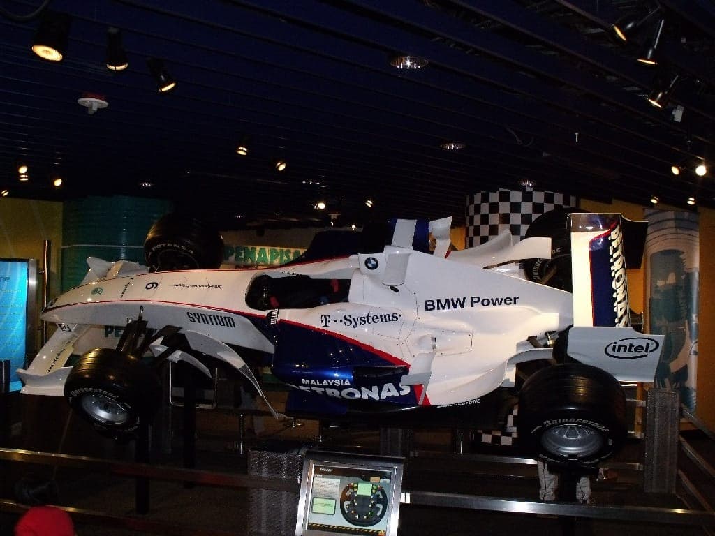 KLCC'deki Petrosains Discovery Centre'nin içinde spot ışıkları altında sergilenen BMW Power logolu tam boyutlu bir Formula 1 yarış arabası sergisi.