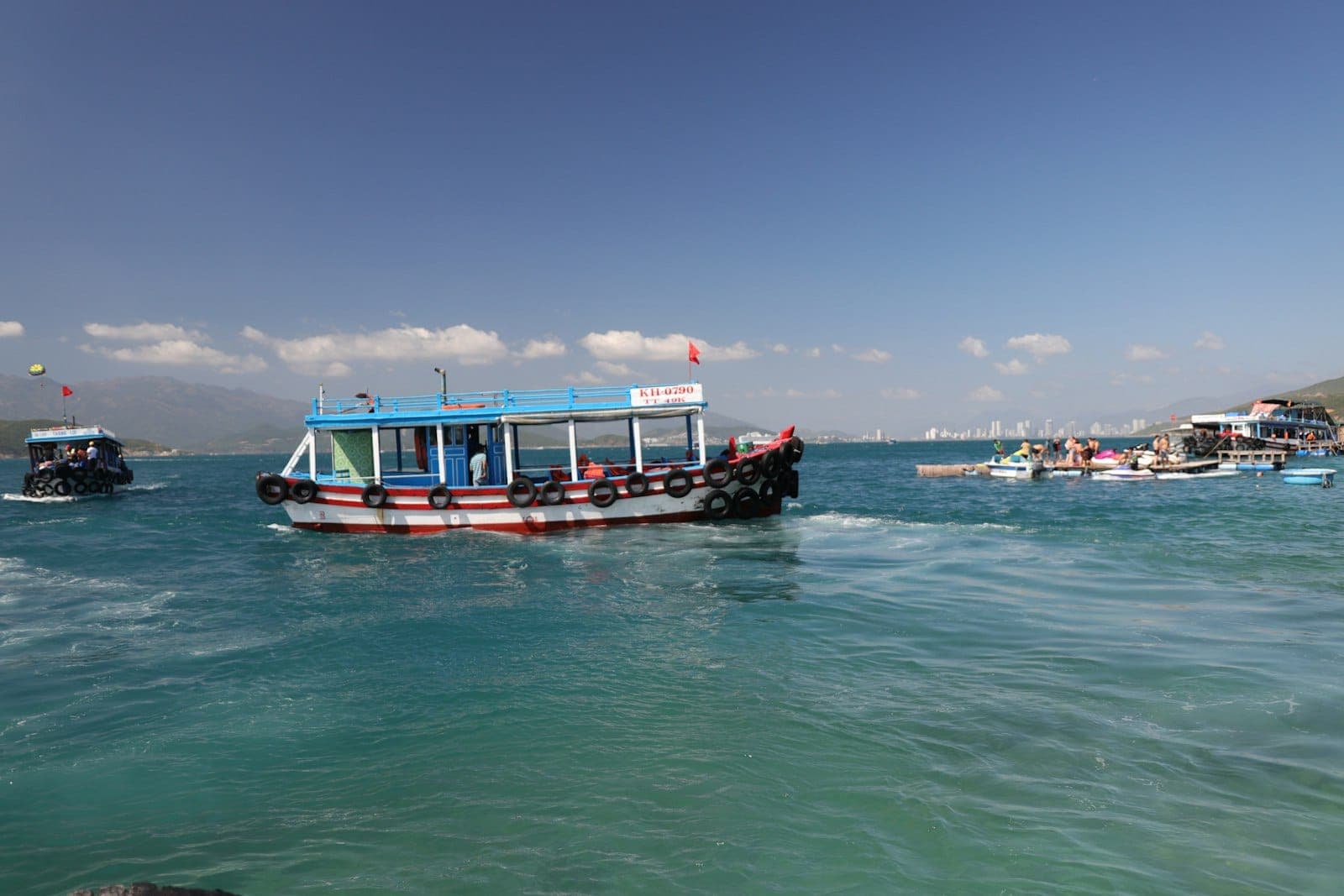 Các thuyền du lịch trên mặt nước xanh tươi sáng gần Phú Quốc, với bầu trời trong xanh và đường bờ biển xa xa, cảnh điển hình của các chuyến tham quan trong ngày quanh quần đảo An Thới.