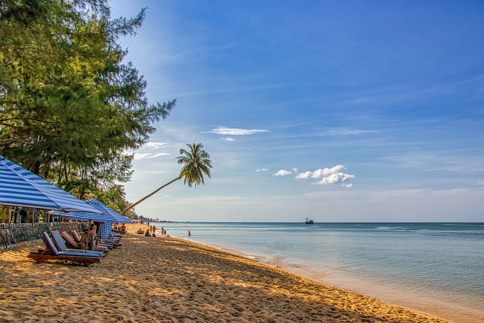 Long Beach à Phu Quoc avec palmiers, transats en bord de mer et eaux turquoise calmes au coucher du soleil