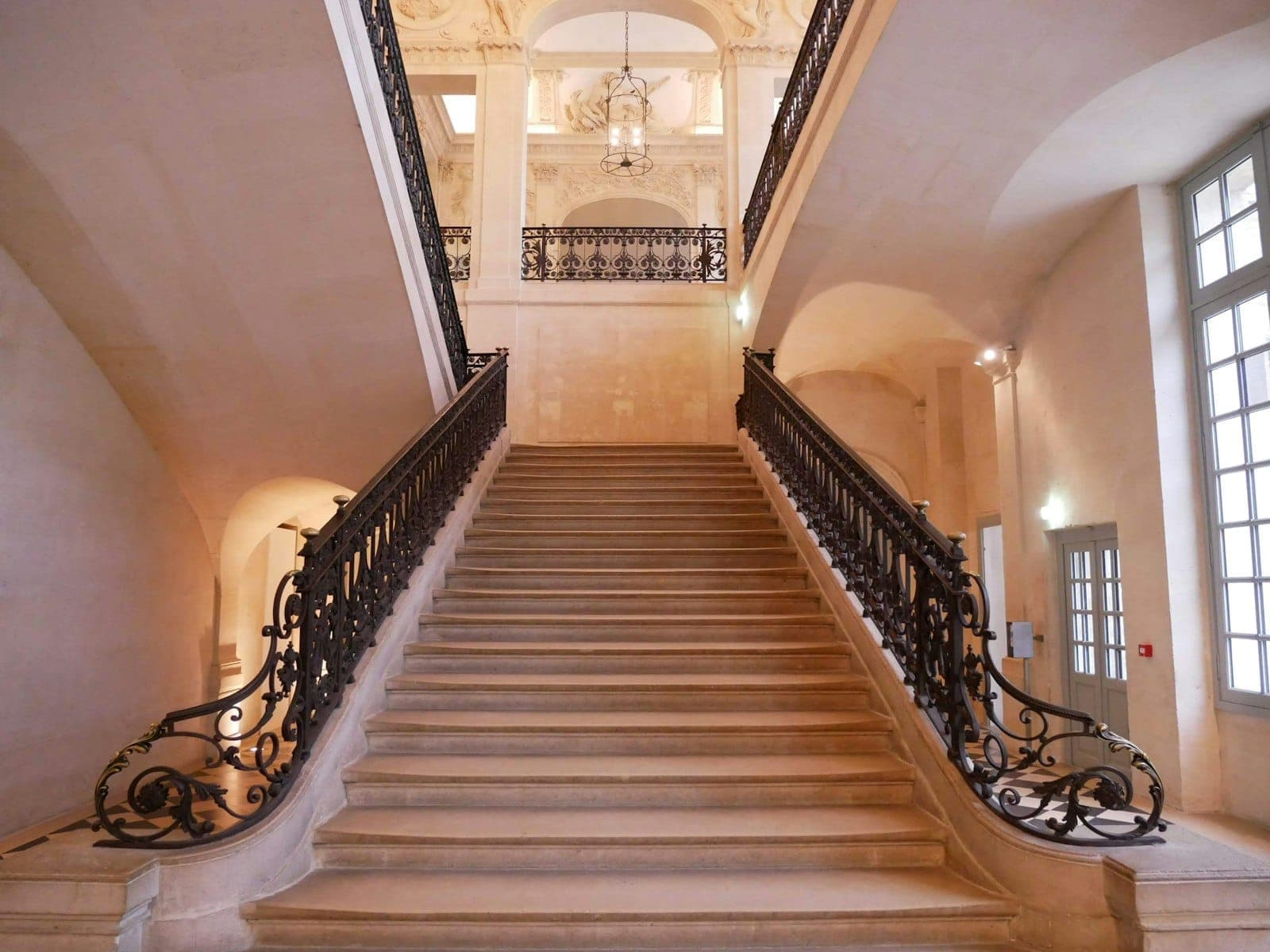 Elegant stone staircase with ornate wrought-iron railings inside the historic Hôtel Salé, original home of the Musée Picasso Paris, illuminated by natural daylight.