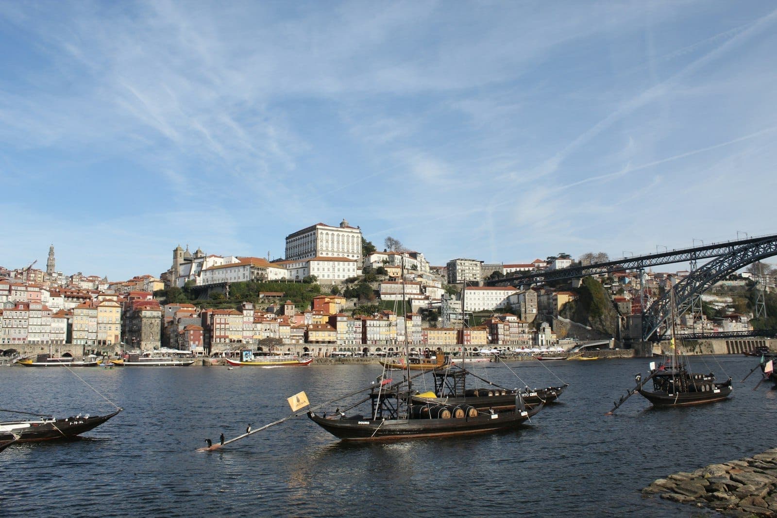 Barche rabelo con botti di vino sul fiume Douro a Porto, con la città storica e i famosi edifici sulle colline sullo sfondo.