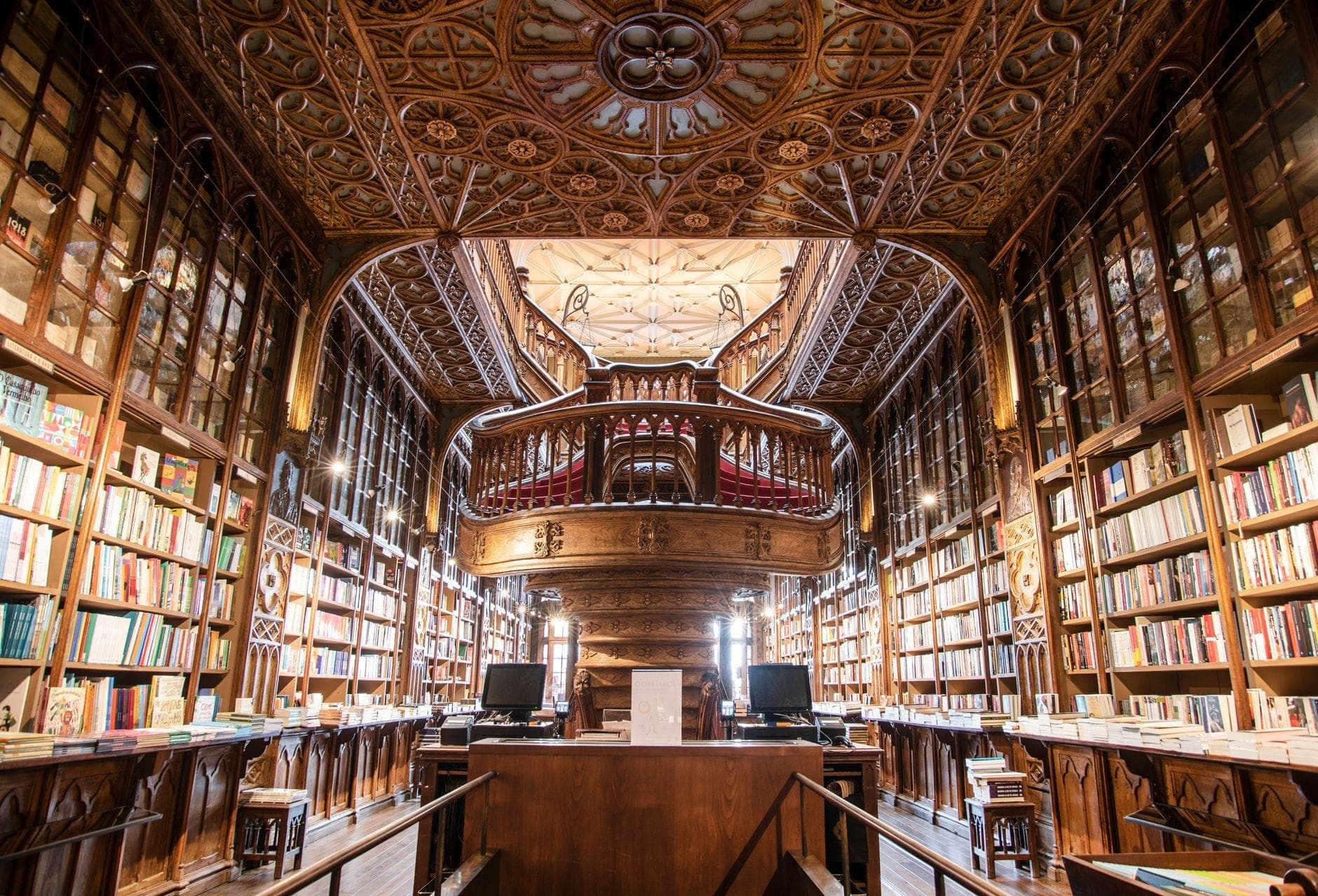 วิวกว้างของภายในไม้ประดับประดาของ Livraria Lello โดดเด่นด้วยชั้นหนังสือแกะสลัก บันไดอันยิ่งใหญ่ และเพดานตกแต่งที่วิจิตรบรรจง