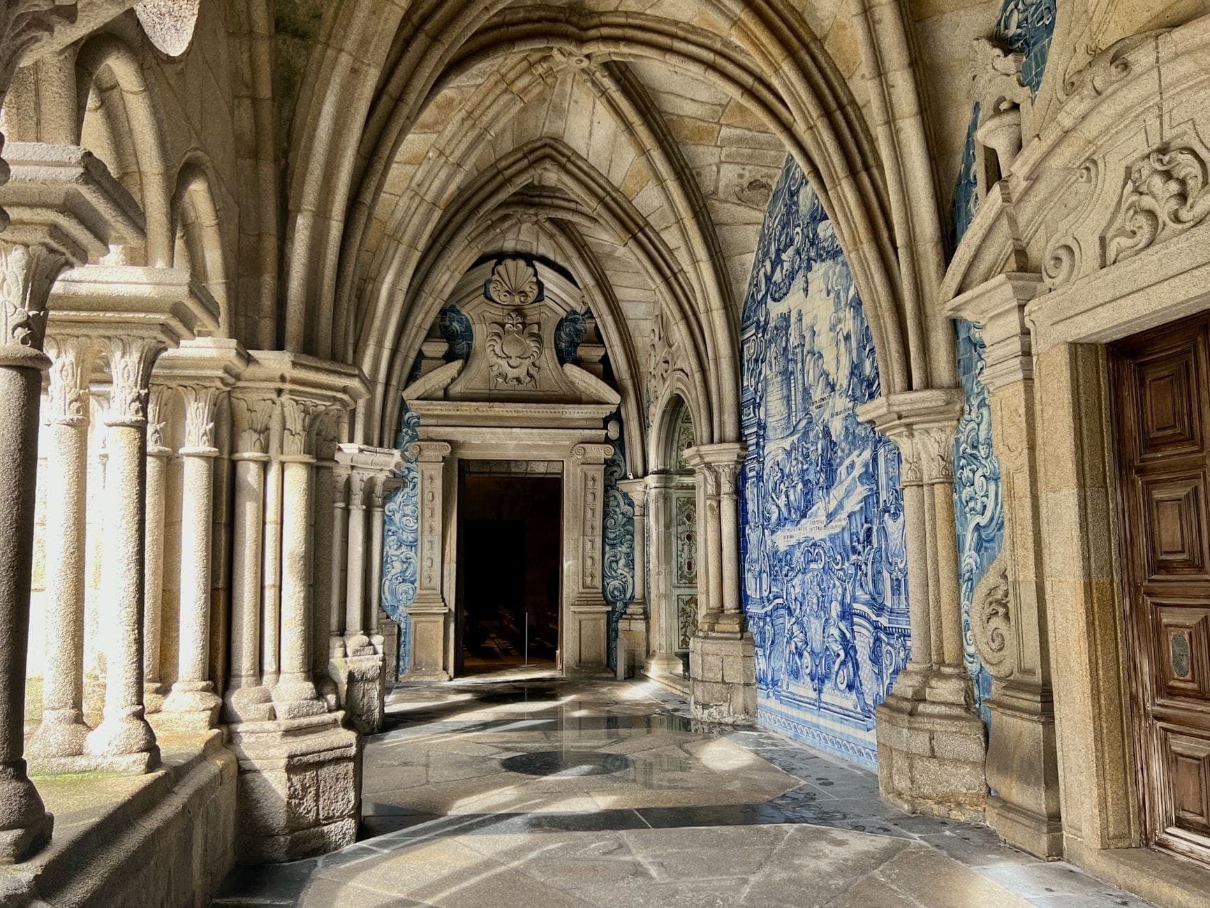 Corredor de pedra em arco com azulejos azuis e brancos retratando cenas históricas nas paredes no Porto, Portugal.