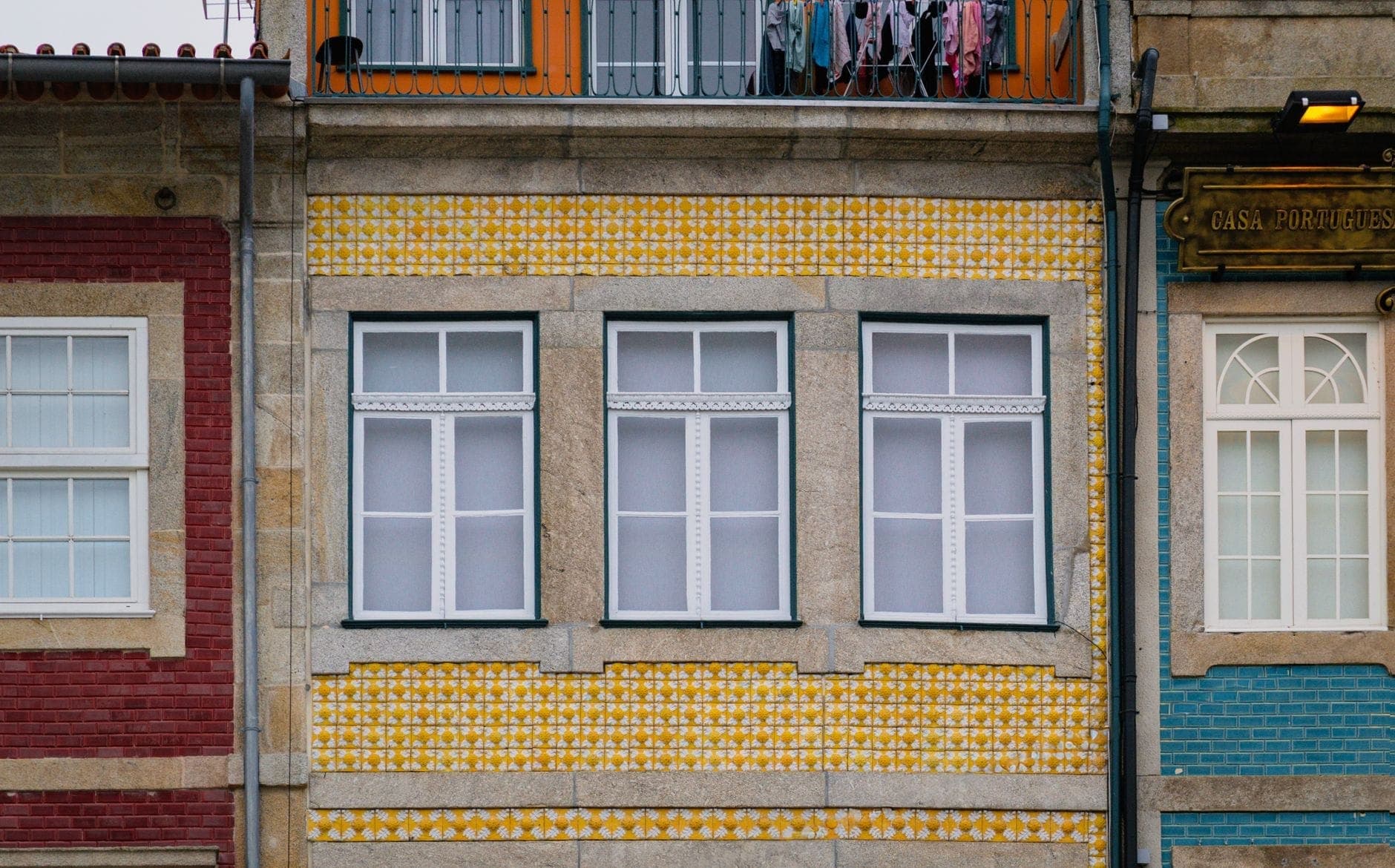 Vista da rua de edifícios residenciais tradicionais do Porto com fachadas de azulejos coloridos em amarelo, vermelho e azul.
