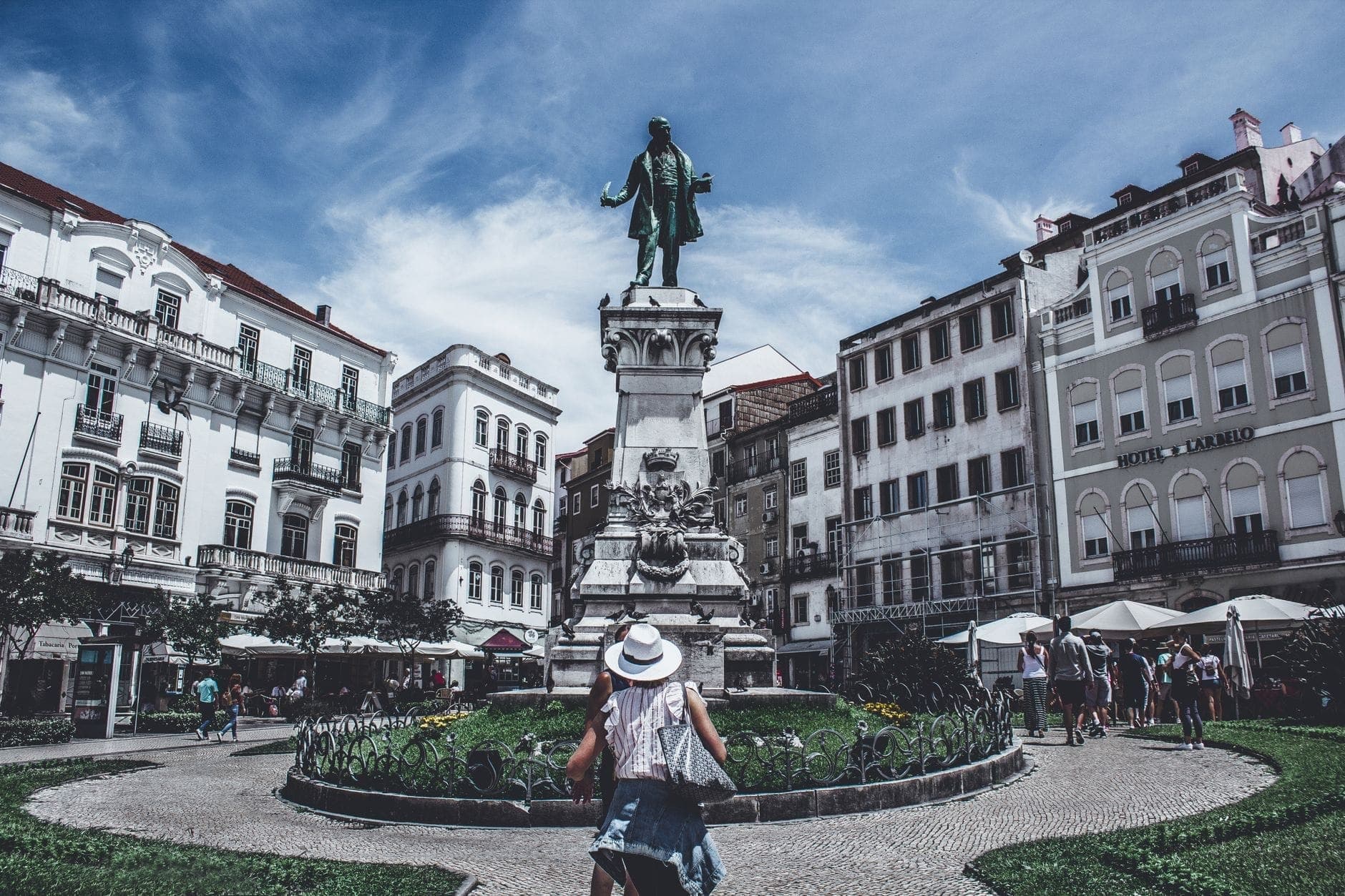 Ludzie spacerują i odpoczywają w pobliżu pomnika Dom Pedro IV na tętniącym życiem placu w Porto, otoczonym klasycznymi białymi budynkami i żywym niebem.