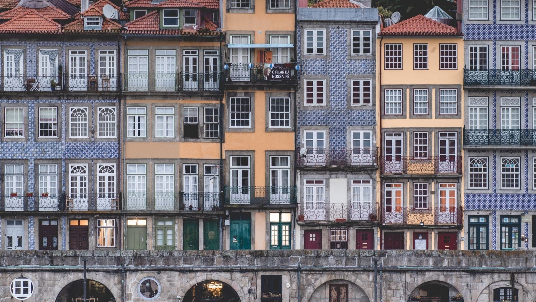 Kolorowe historyczne fasady z kafelkowanymi ścianami i balkonami w Porto, Portugalia, sfotografowane na wprost, podkreślające wyjątkowy charakter i detale architektoniczne.