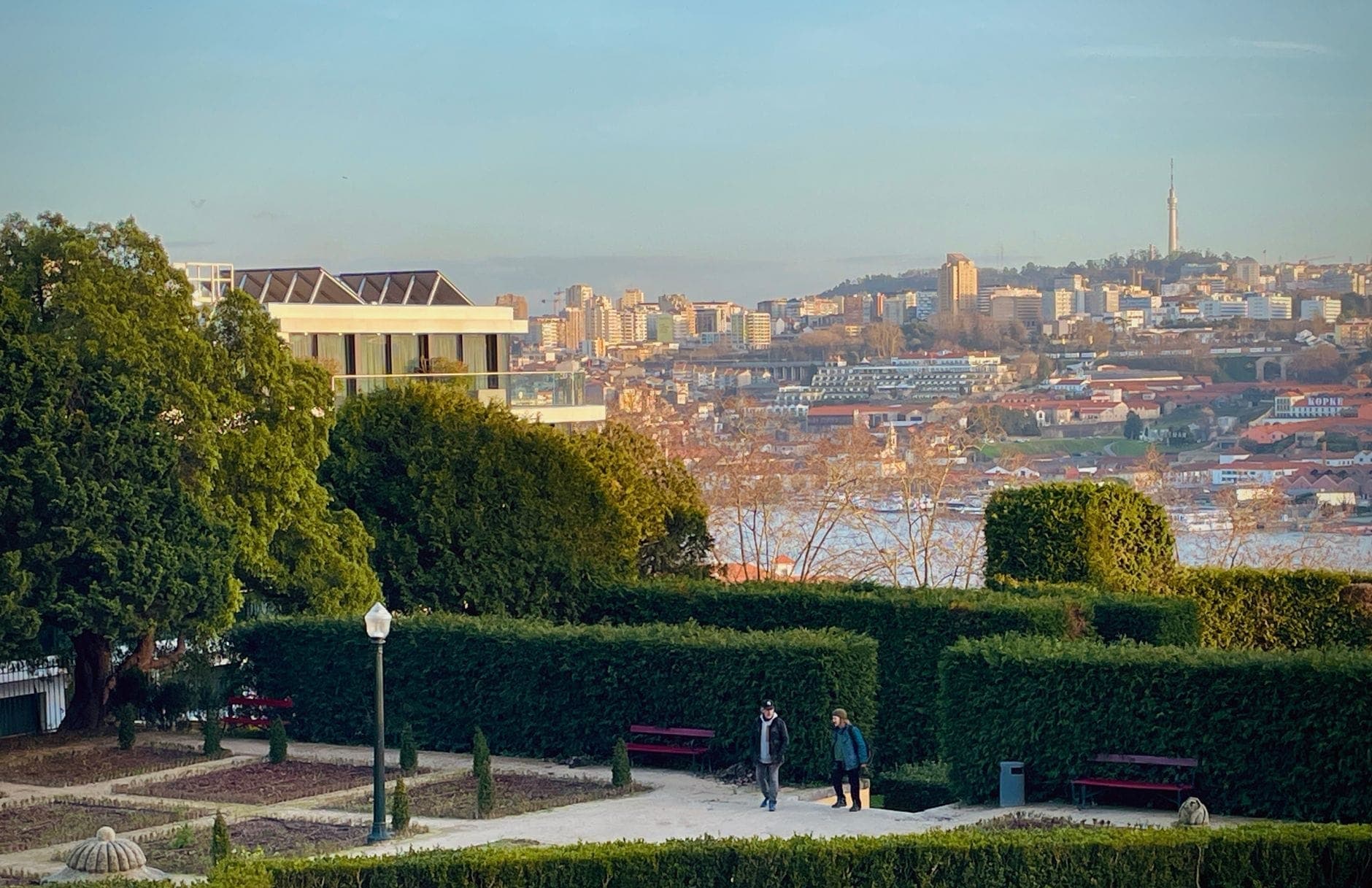 Gepflegter formaler Garten mit Hecken, Bänken und Bäumen mit Blick auf die Stadtlandschaft von Porto und den Fluss Douro.