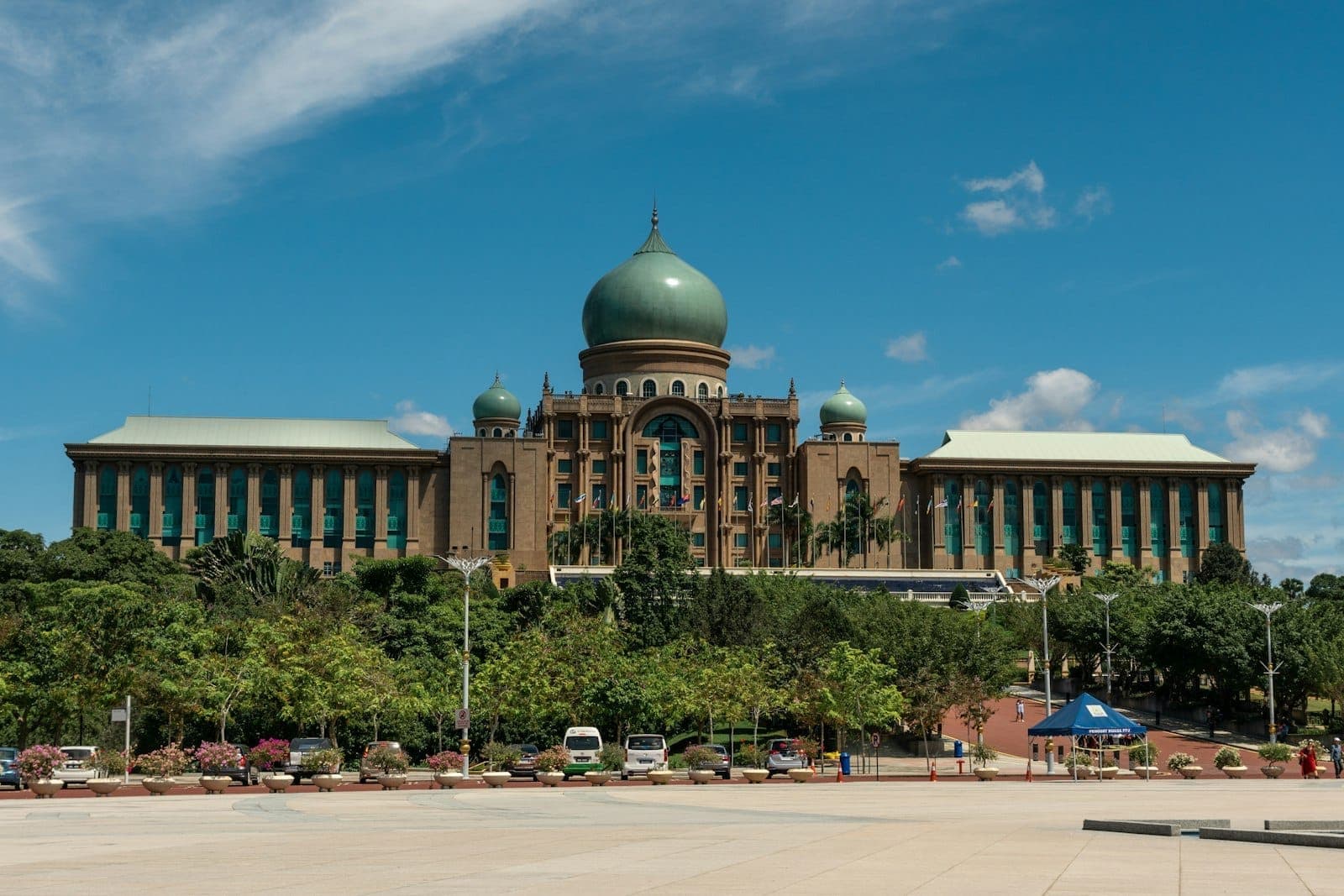 Perdana Putra'nın görkemli kubbesi, Putrajaya'nın özenle bakımlı yeşilliklerinin üzerinde yükselirken parlak ve hafif bulutlu bir gökyüzü altında huzur yayıyor.