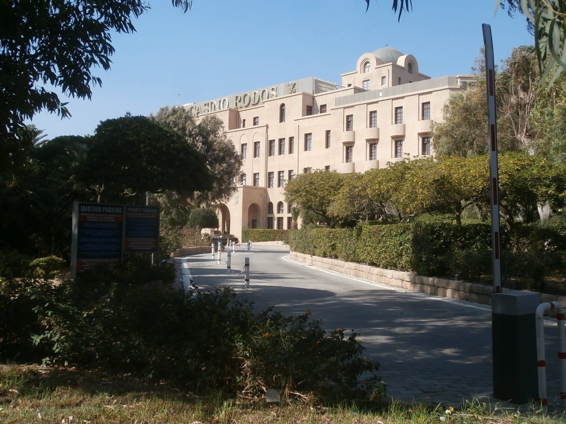 Grande Albergo delle Rose, qui abrite le Casino Rodos, baigné de soleil avec sa façade imposante et son entrée bordée d'arbres dans la Ville Nouvelle de Rhodes.
