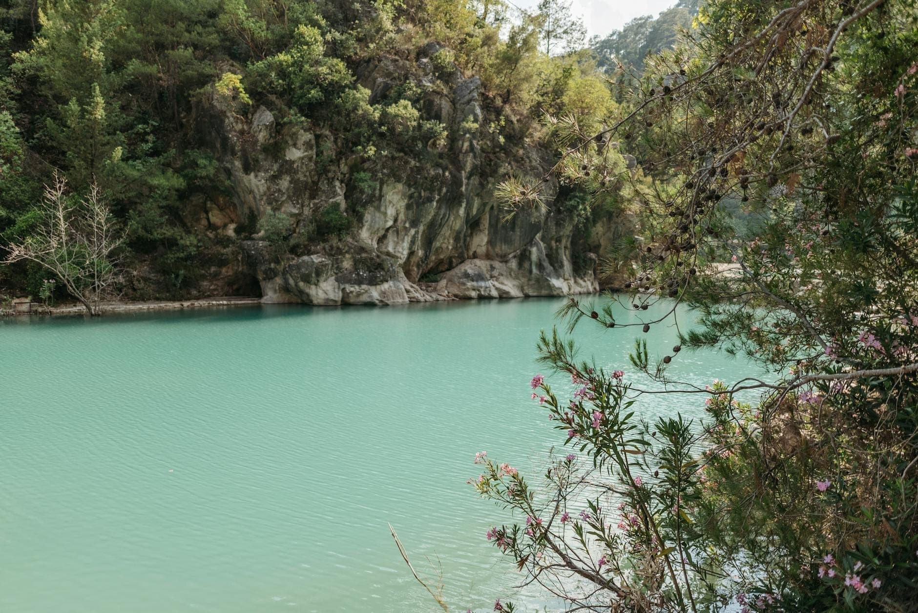 Turkusowe sztuczne jezioro otoczone skalistymi klifami i drzewami, krajobraz w Seven Springs na Rodos.