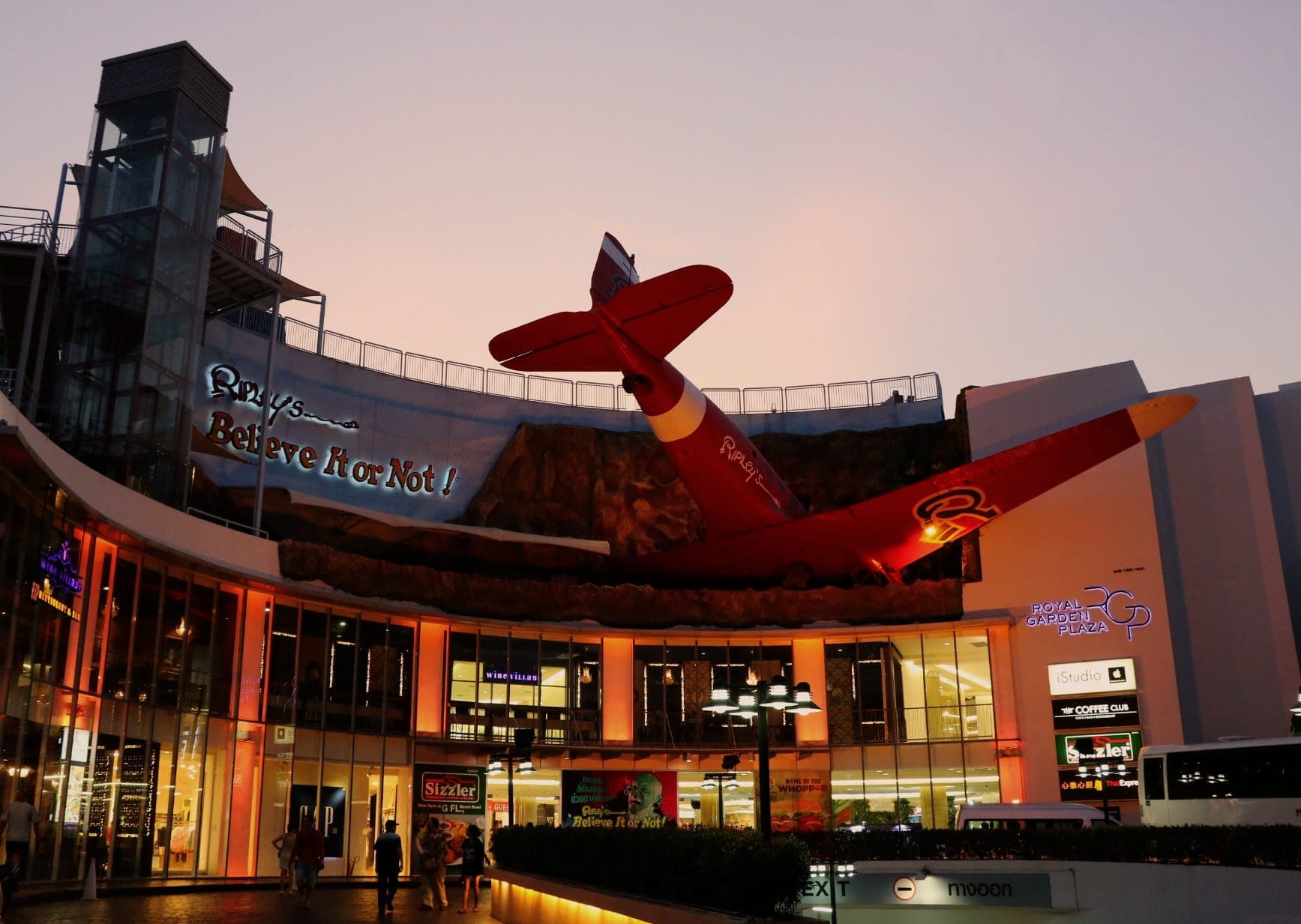 Ngoại thất của Ripley's Believe It or Not! Pattaya lúc hoàng hôn, nổi bật với chiếc máy bay màu đỏ ấn tượng phía trên lối vào Royal Garden Plaza.