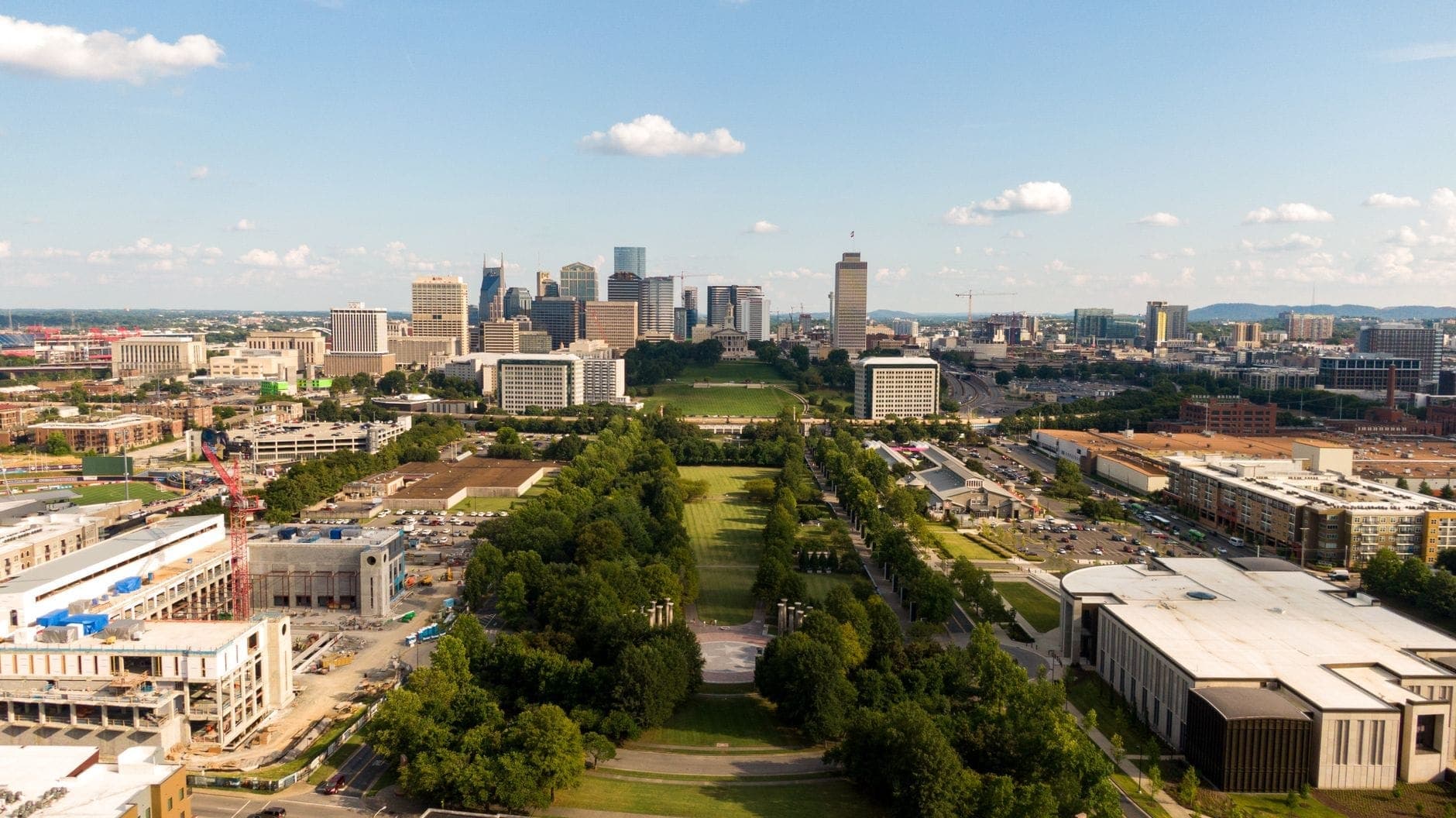 Vista aerea di un lungo parco verde che si estende verso lo skyline di Nashville con ampi viali alberati e lussureggianti prati.
