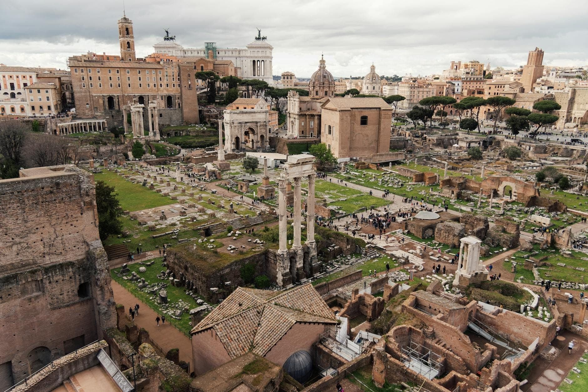 วิวกว้างของแหล่งโบราณคดี Forum Romanum พร้อมซากปรักหักพังโบราณและอาคารสำคัญใต้ท้องฟ้ามีเมฆในกรุงโรม ประเทศอิตาลี