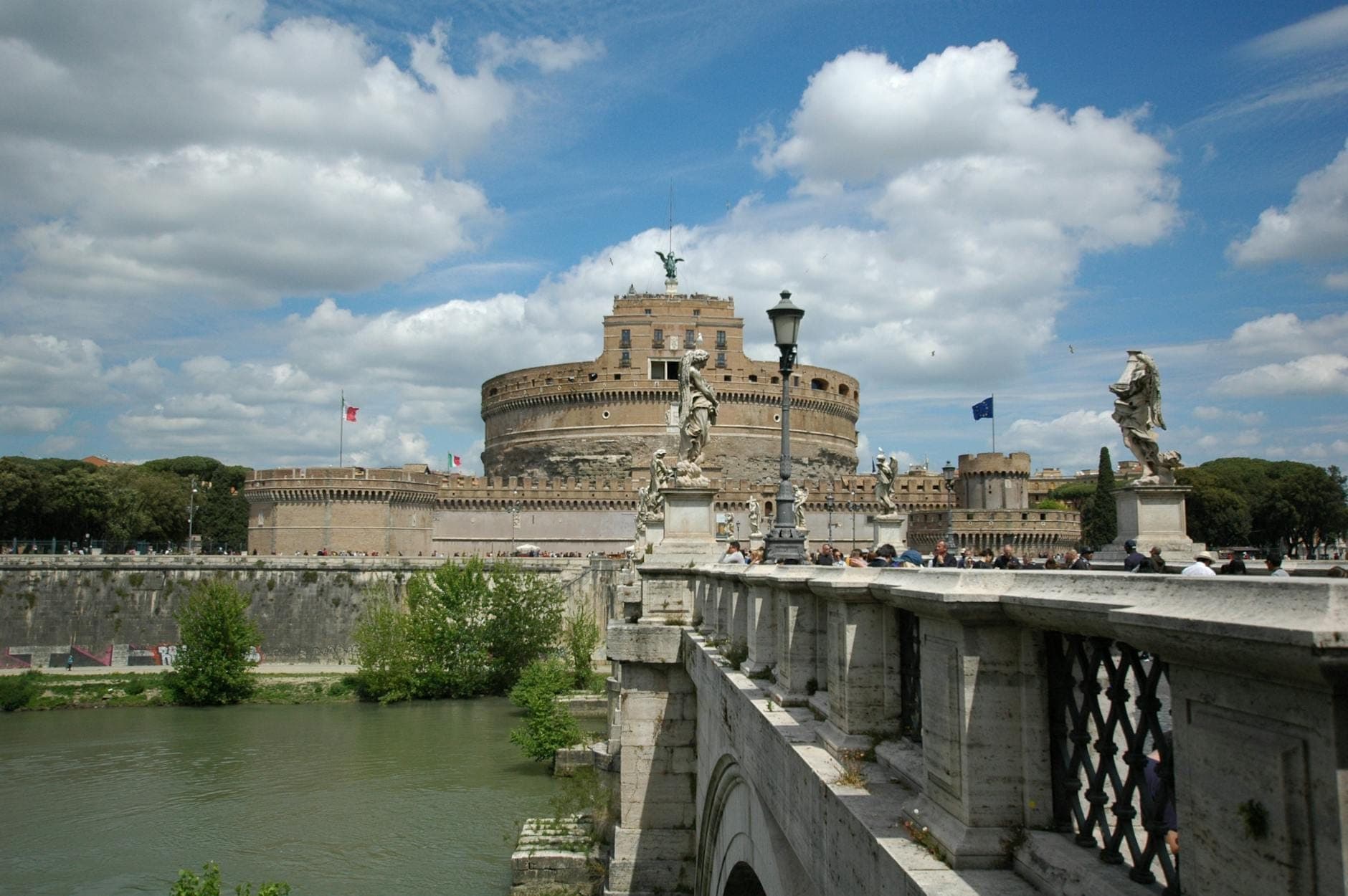 Weitwinkelansicht des Castel Sant'Angelo mit der Bogenbrücke und Steinstatuen, beliebtes familienfreundliches Ausflugsziel in Rom, unter einem strahlend blauen Himmel.