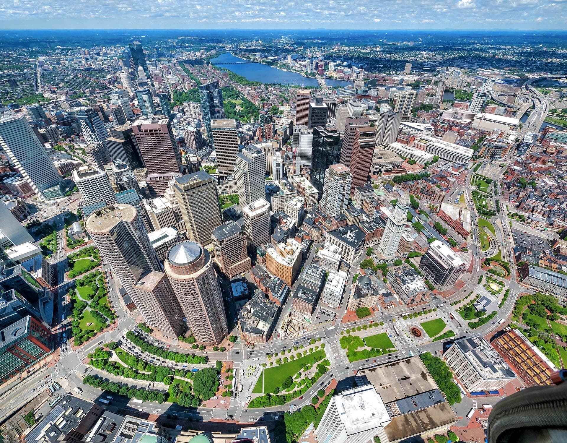 Vue aérienne du centre-ville de Boston avec le Rose Kennedy Greenway serpentant entre les gratte-ciel, les parcs verdoyants et les rues de la ville par une journée ensoleillée.