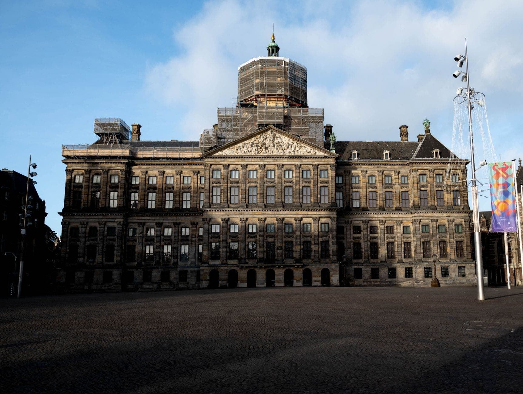 Frontansicht des Königlichen Palastes Amsterdam am Dam-Platz mit seiner imposanten Architektur des Goldenen Zeitalters unter hellem Himmel.
