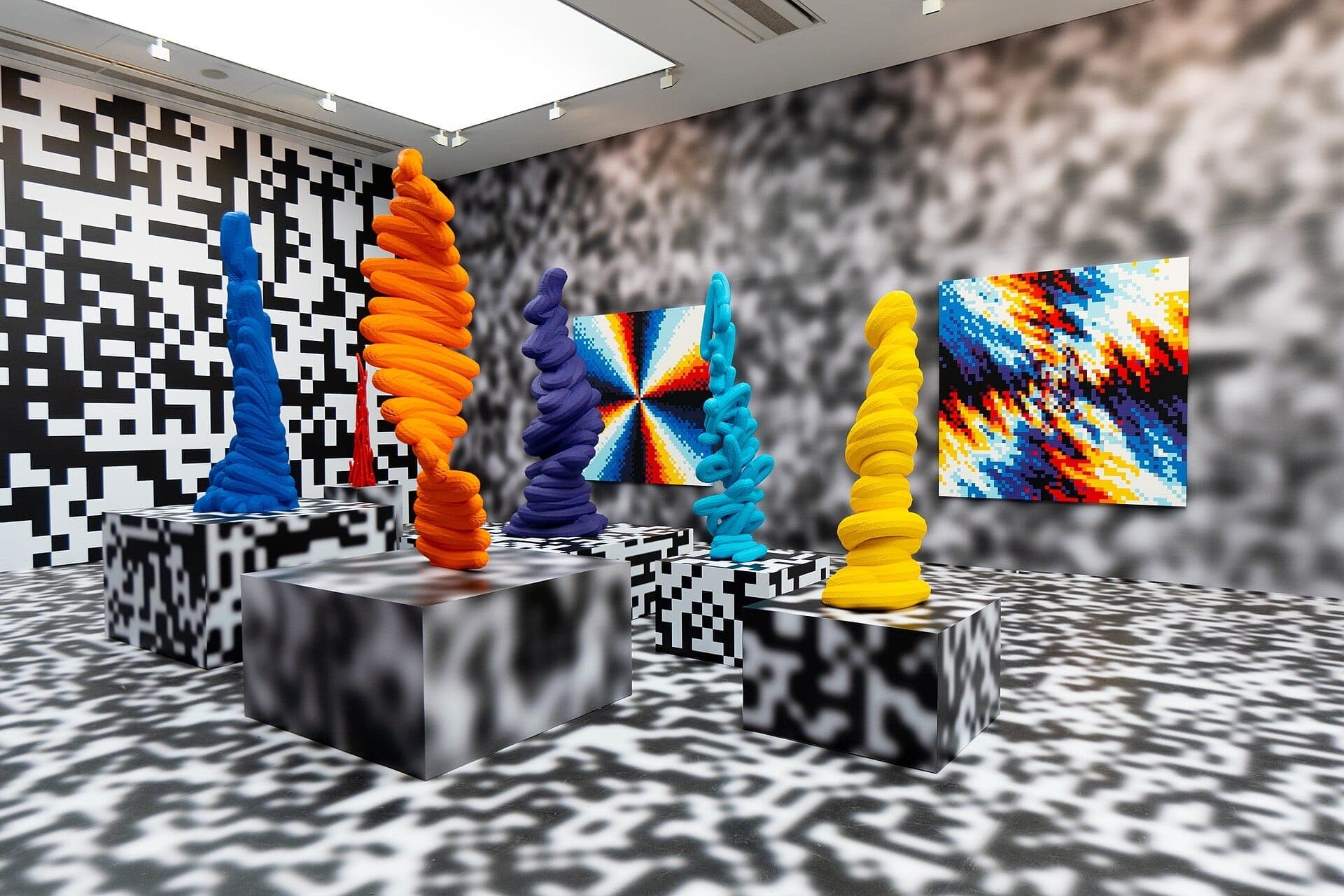 Farbenfrohe abstrakte Skulpturen und pixelierte Gemälde in einem hellen, modernen Galerieraum der Saatchi Gallery, Chelsea, London.