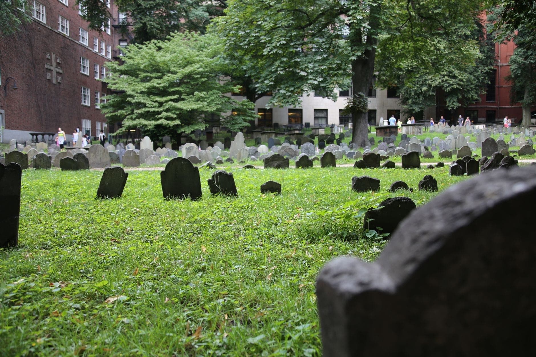 Vieux cimetière avec des pierres tombales historiques entourées d'arbres et de gazon, évoquant l'atmosphère mystérieuse des procès en sorcellerie de Salem.