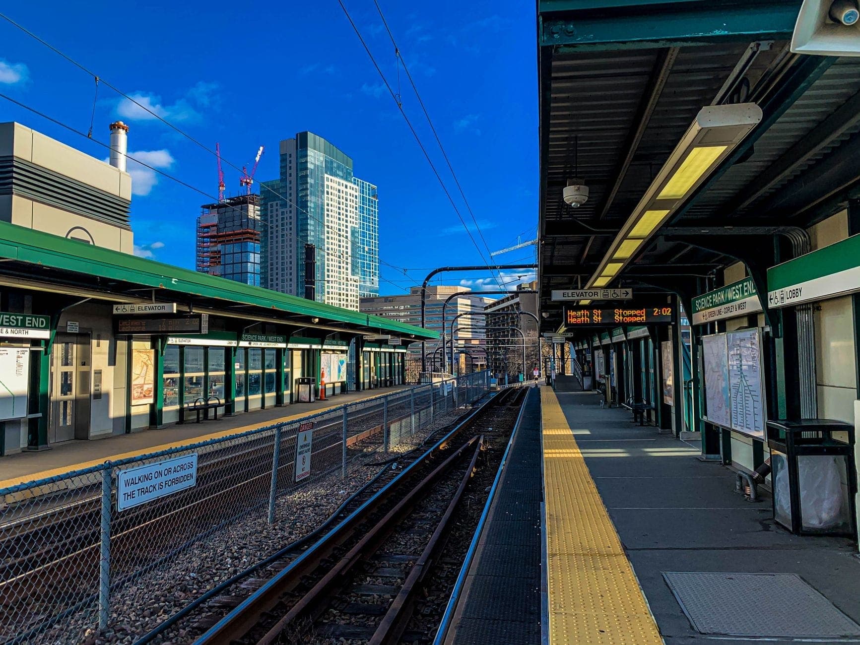 Quai extérieur de la North Station de Boston, avec des bâtiments modernes en arrière-plan et une signalisation claire au-dessus des voies.