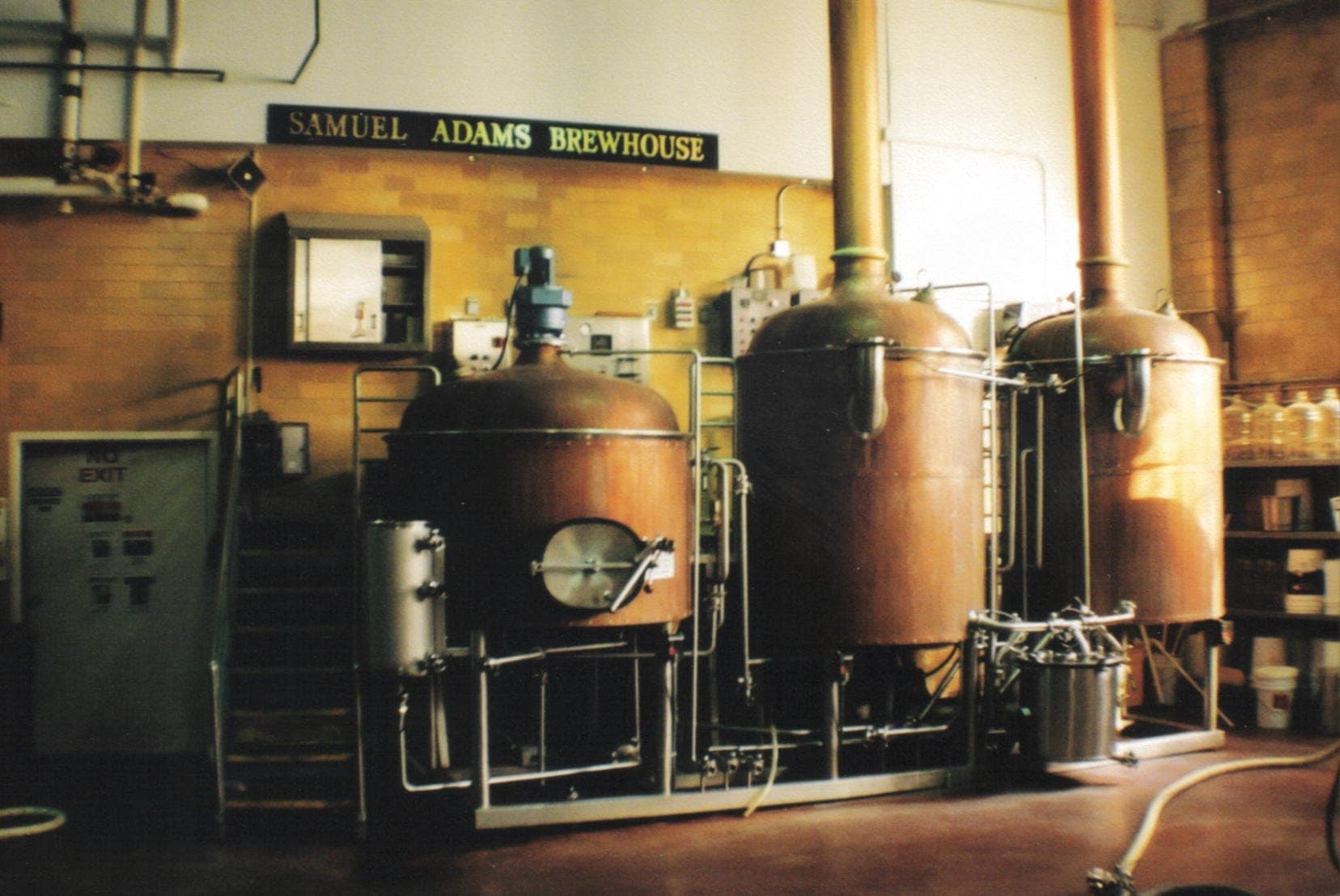 Cuves de brassage en cuivre et équipements industriels à l'intérieur du Samuel Adams Brewhouse, avec des murs en briques jaunes et un éclairage naturel doux.