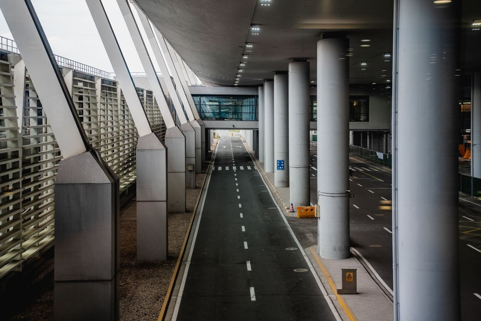 Zona de llegadas moderna del Aeropuerto Francisco Sá Carneiro de Oporto, con amplia calzada, pasarela elevada y diseño de vidrio y acero