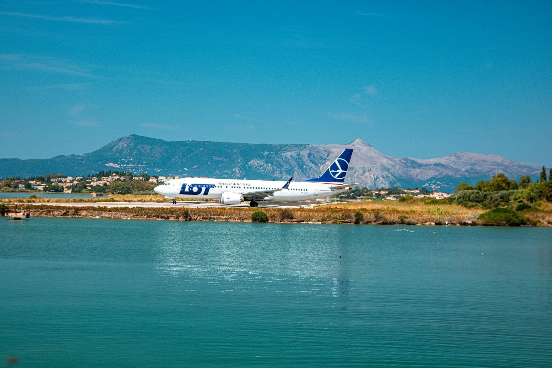 Avión comercial en la pista del aeropuerto de Cerdeña con montañas y paisaje costero al fondo bajo un cielo azul