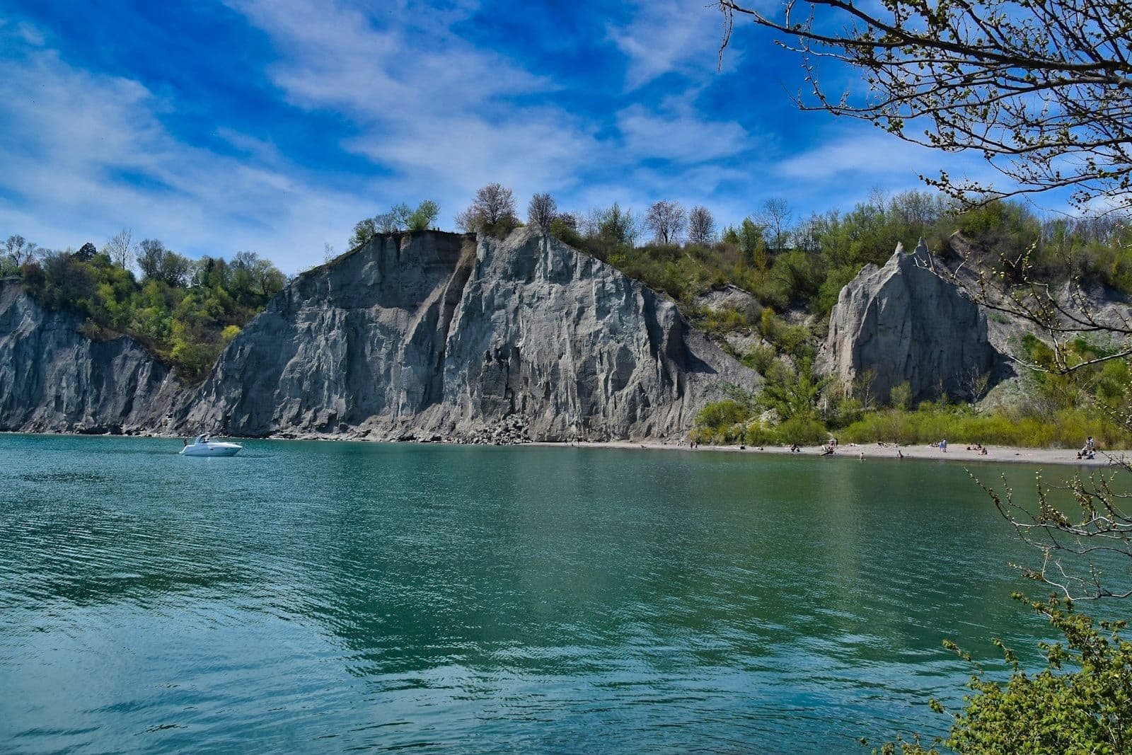 Una vista spettacolare delle Scarborough Bluffs che si innalzano sulle acque azzurre del lago Ontario sotto un cielo limpido con qualche nuvola sparsa.