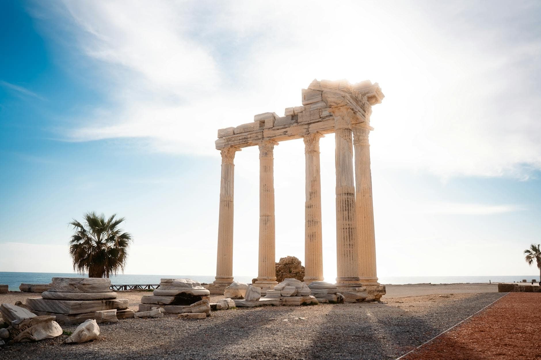 Die fünf Säulen des Apollontempels erheben sich an der Küste im dramatischen Sonnenlicht, flankiert von Palmen am Mittelmeer in Side, Türkei.