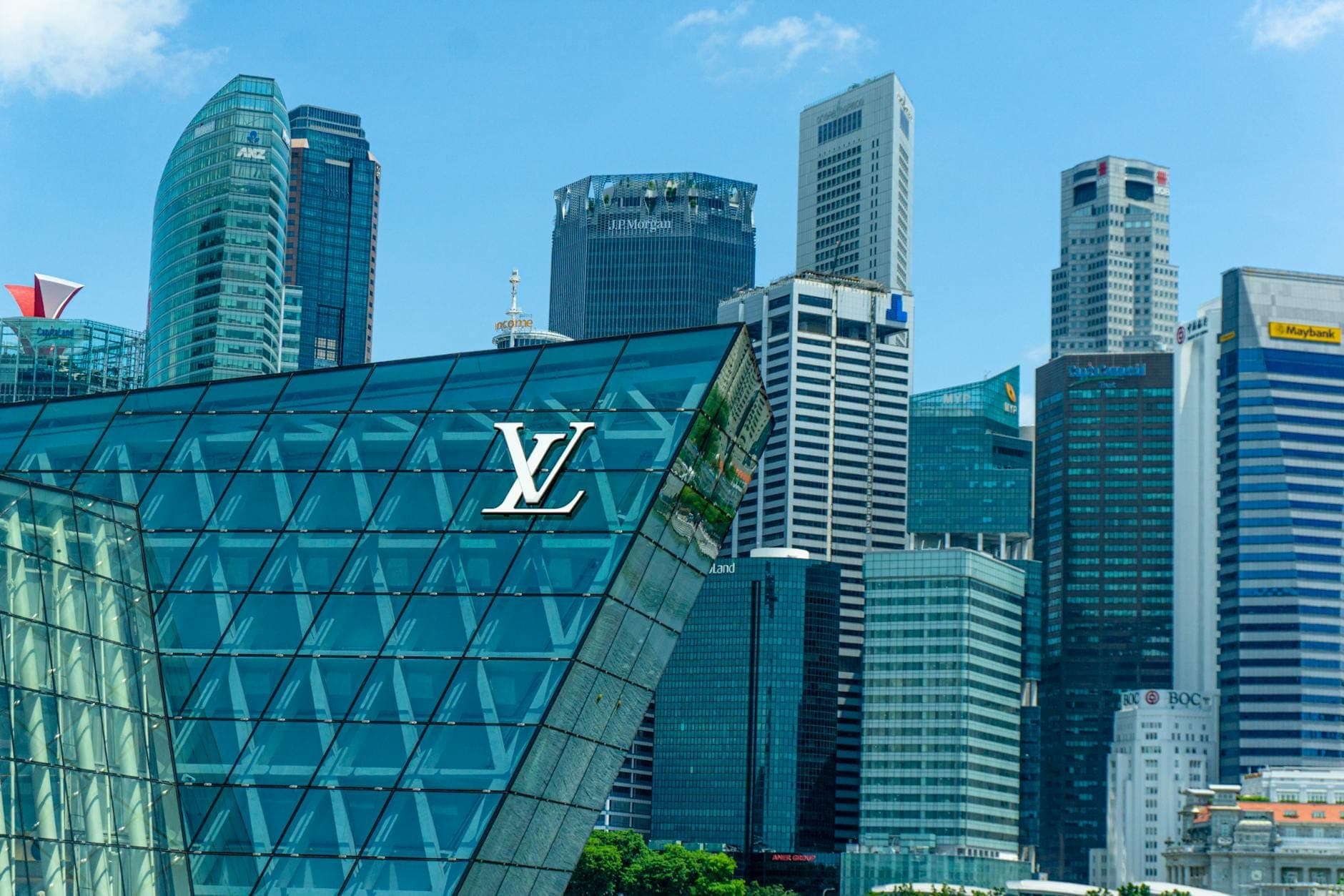 อาคาร Louis Vuitton ที่มีสถาปัตยกรรมกระจกโดยมีเส้นขอบฟ้าสมัยใหม่ของ Singapore เป็นฉากหลังในวันที่อากาศแจ่มใส