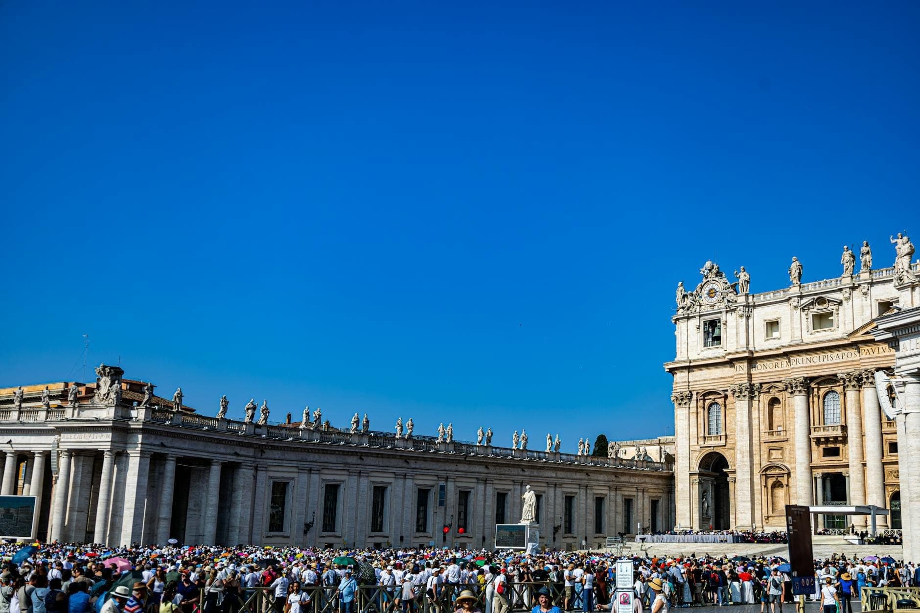 Grande folla di turisti in coda fuori dalla Basilica di San Pietro sotto un cielo azzurro brillante nella Città del Vaticano, Roma.
