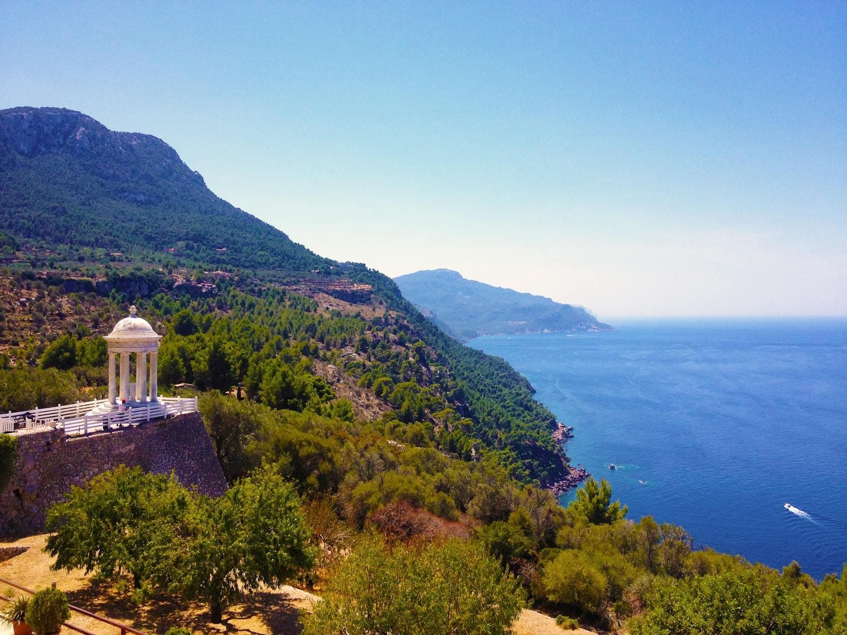 Weiter Blick auf die Marmorrotunde von Son Marroig über den dramatischen Tramuntana-Klippen und dem funkelnden blauen Meer unter klarem Himmel im Nordwesten Mallorcas.