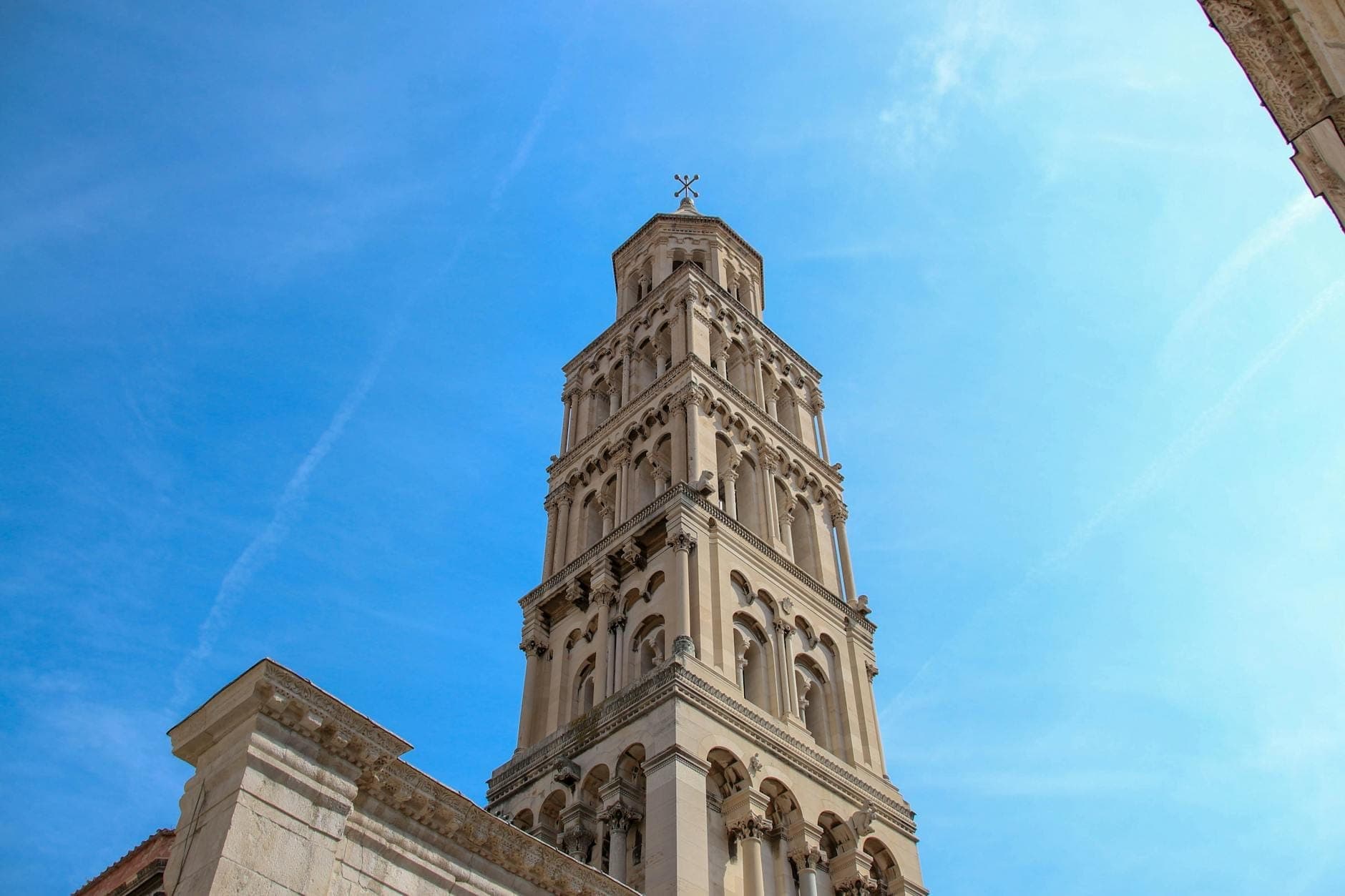 Haute tour clocher en pierre de la cathédrale de Split, vue d'en bas sur un ciel bleu vif, mettant en valeur une attraction payante de premier ordre.