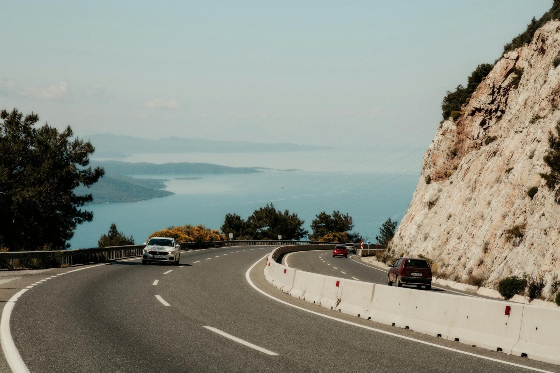 Strada costiera con auto che percorrono un tratto a strapiombo sul mare, con vista sul blu Mar Adriatico vicino a Spalato, Croazia.