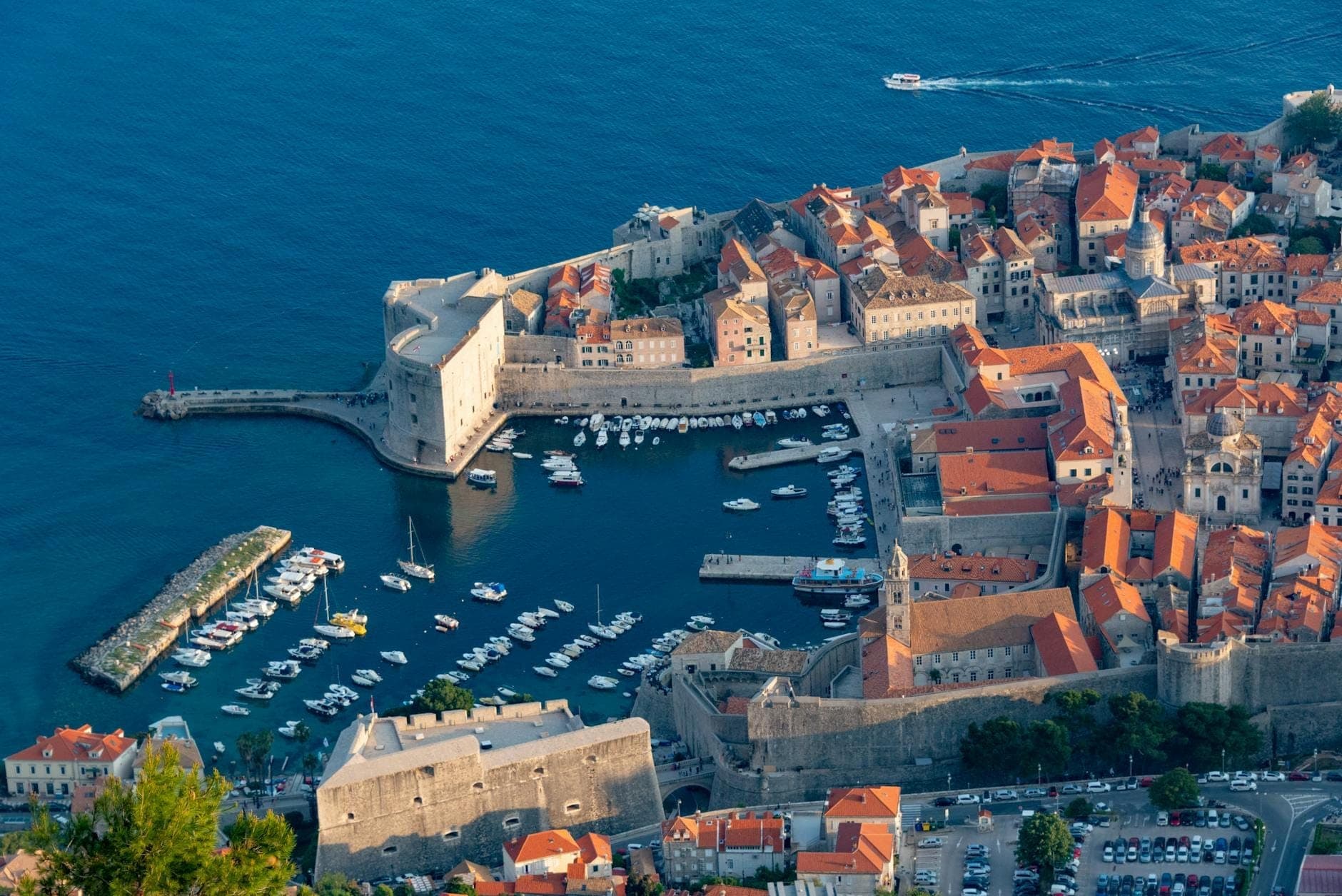 มุมมองทางอากาศของท่าเรือเก่าของ Dubrovnik พร้อมกำแพงหิน มารีนา และเรือ โดยมองเห็นทะเล Adriatic สีฟ้า