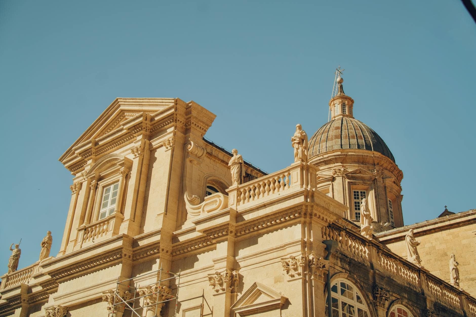 Nahaufnahme der Fassade und Kuppel der Kirche des Heiligen Blasius in Dubrovnik, in Sonnenlicht getaucht vor einem klaren blauen Himmel.