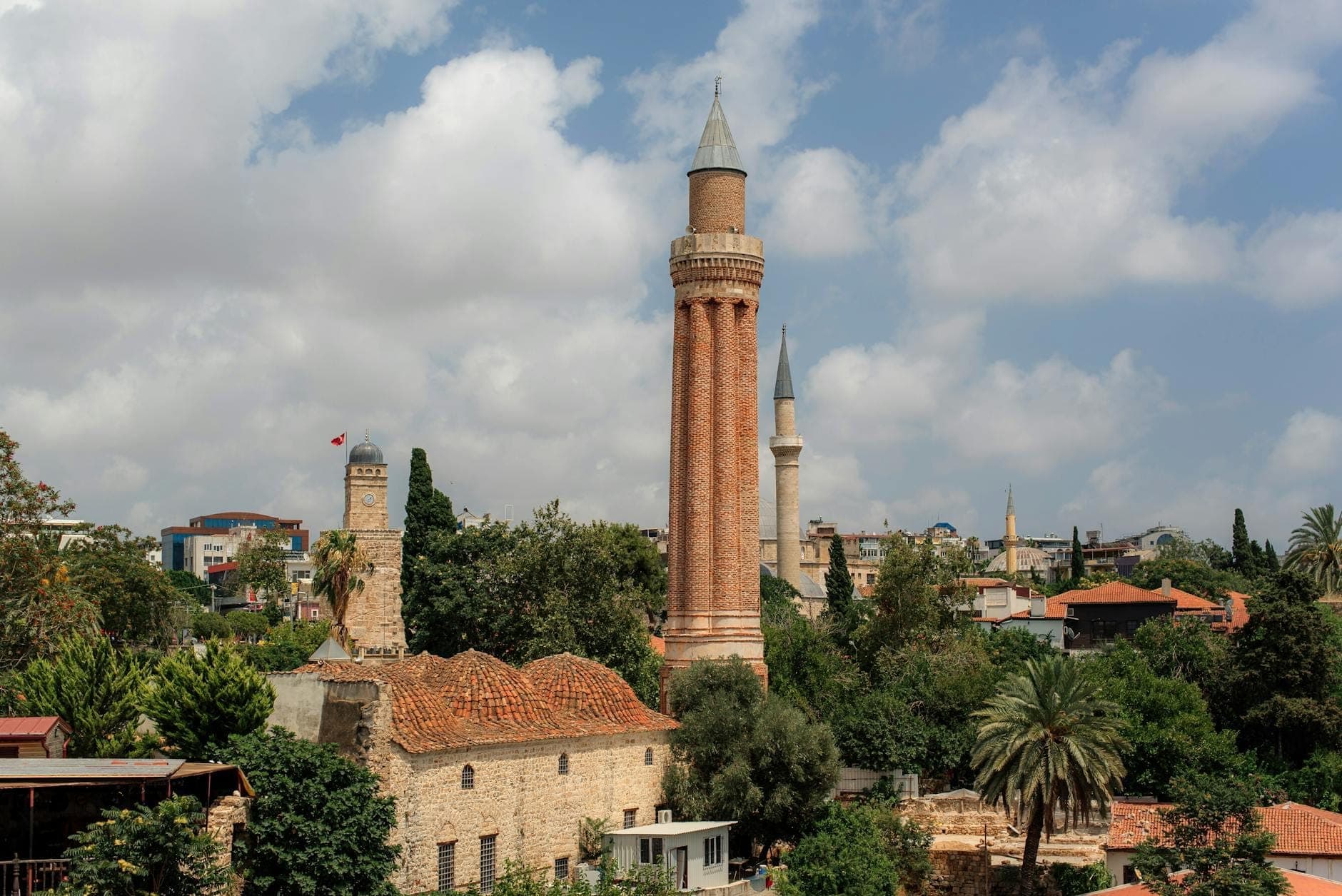 Tagesansicht der historischen Sultan-Alaaddin-Moschee mit ihrem markanten gerillten Minarett, das über den Dächern und Palmen der Kaleiçi-Altstadt in Antalya aufragt.